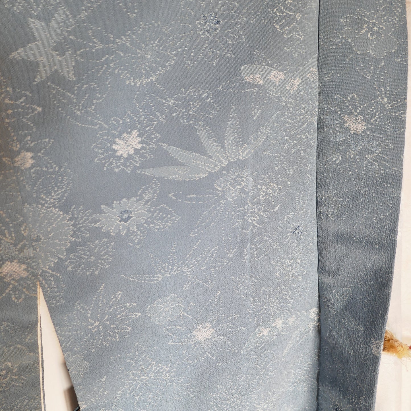 Vue rapprochée du tissu extérieur du haori en soie bleu clair, orné de motifs de feuillage et fleurs japonaises.