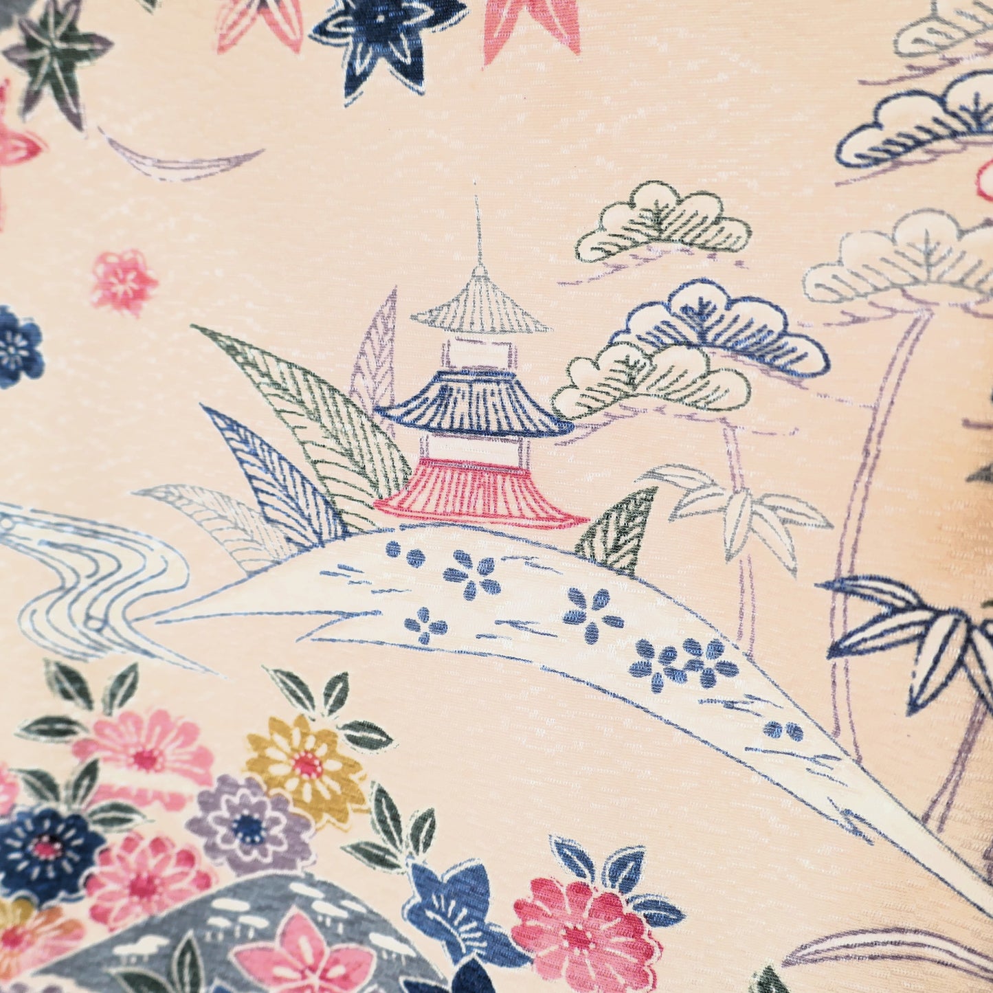 Détail d’un haori vintage en soie avec pagode rouge et végétation stylisée sur fond beige clair