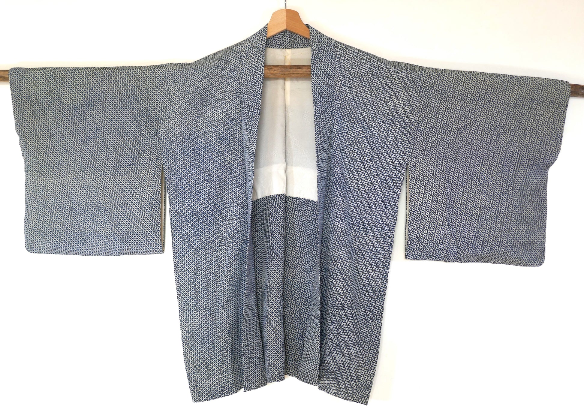 Haori vintage japonais en soie bleu marine, motif shibori régulier, vu de face sur cintre.
