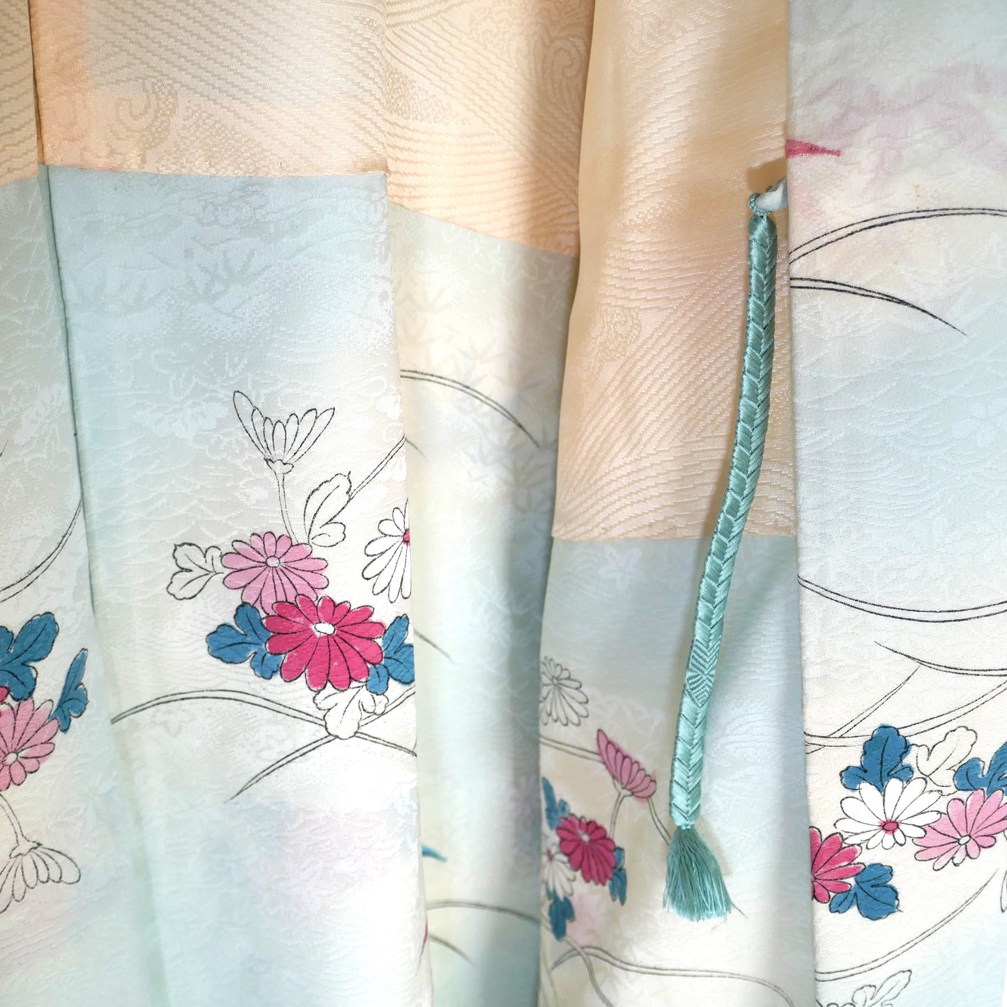 Zoom sur le haori en soie avec attache haori himo vert d’eau et motifs floraux japonais.