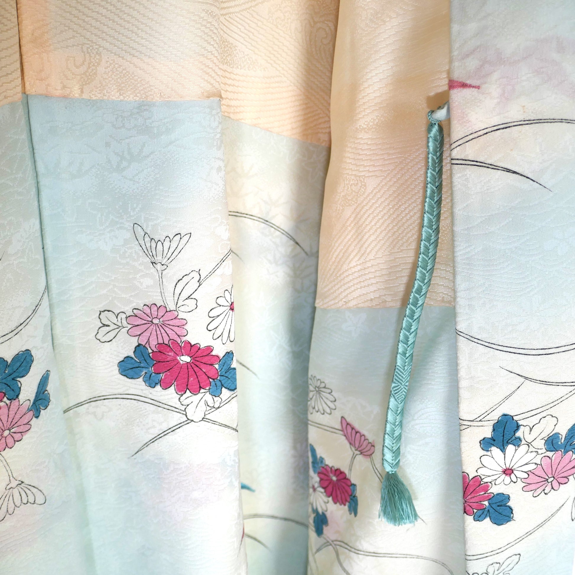 Zoom sur le haori en soie avec attache haori himo vert d’eau et motifs floraux japonais.