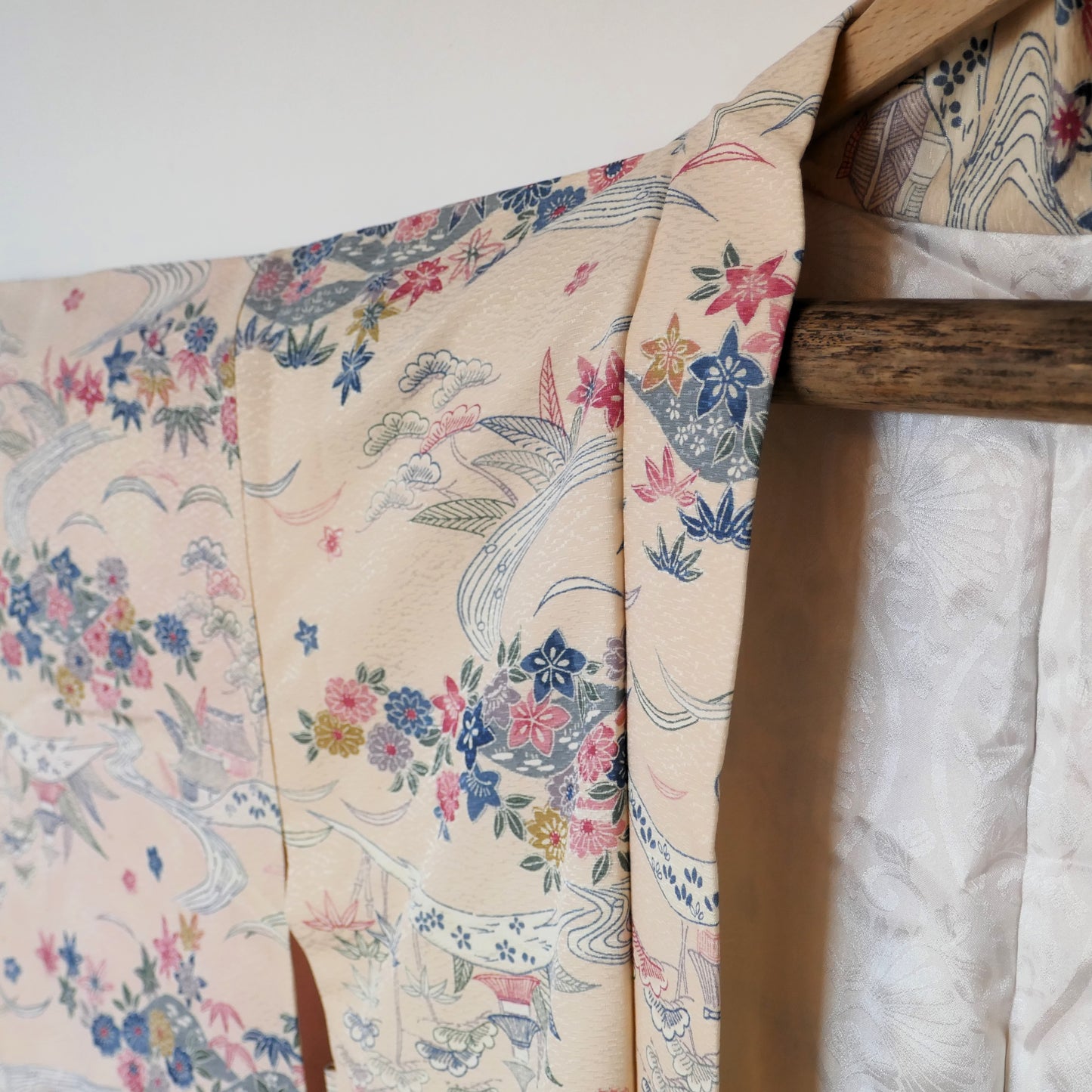 Détail des motifs floraux et des rivières tissés sur le haori vintage japonais en soie beige rosé.