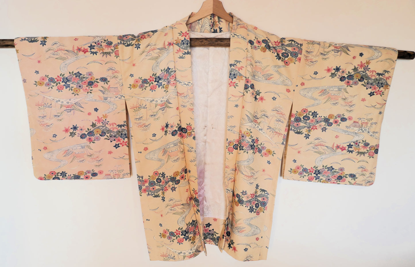Vue de face du haori vintage en soie avec motifs de paysages japonais, rivières et fleurs colorées.