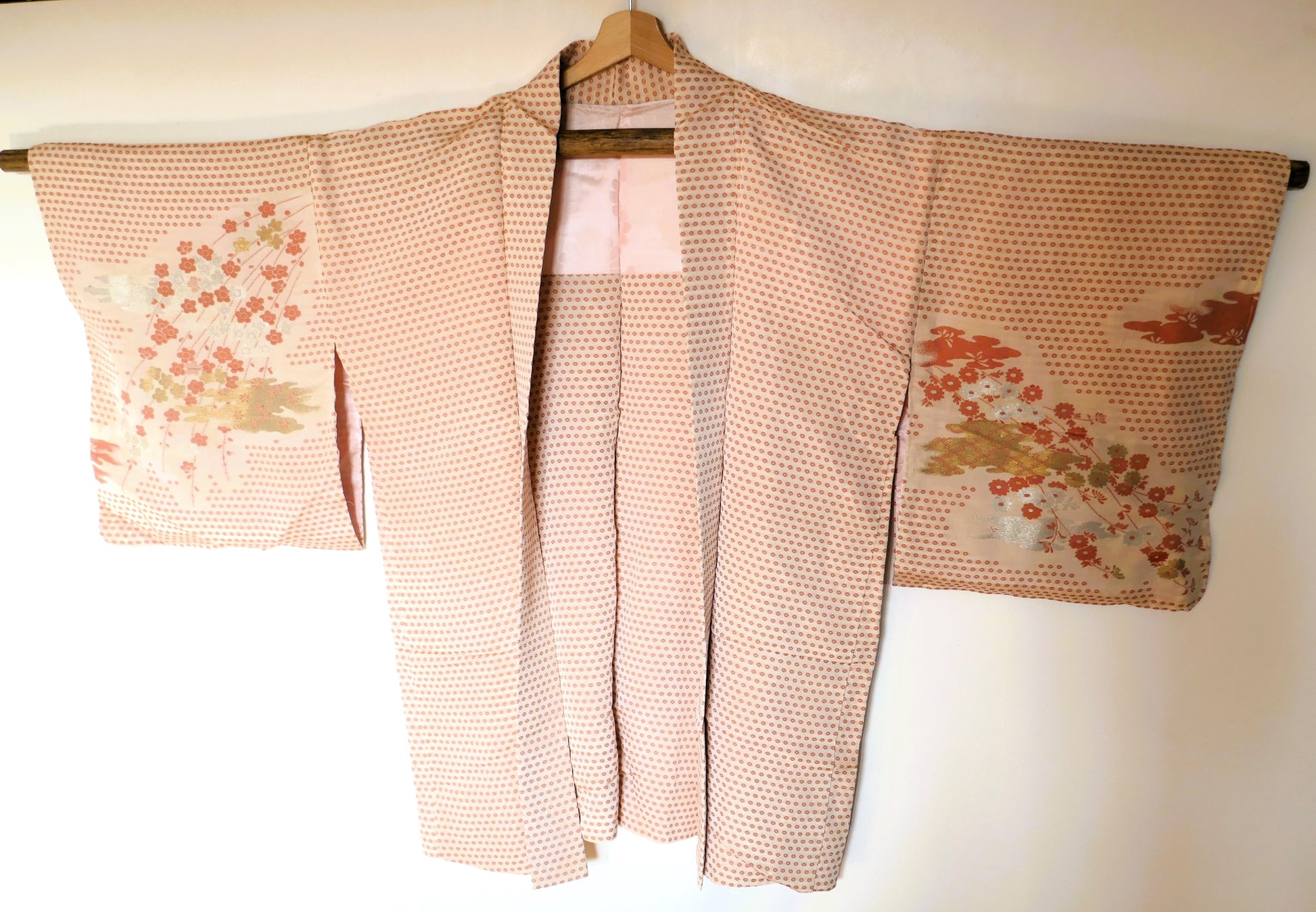 Haori vintage japonais en soie rose saumonée avec motifs de fleurs de prunier vu de face.