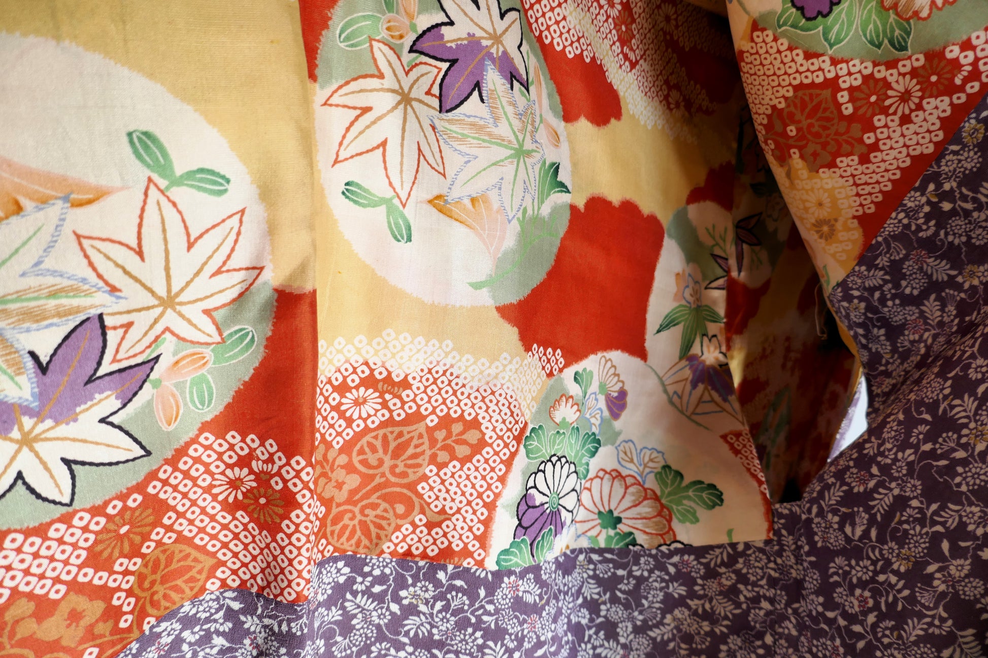 Gros plan sur la doublure intérieure du haori avec motifs de feuilles de momiji et nuages colorés.