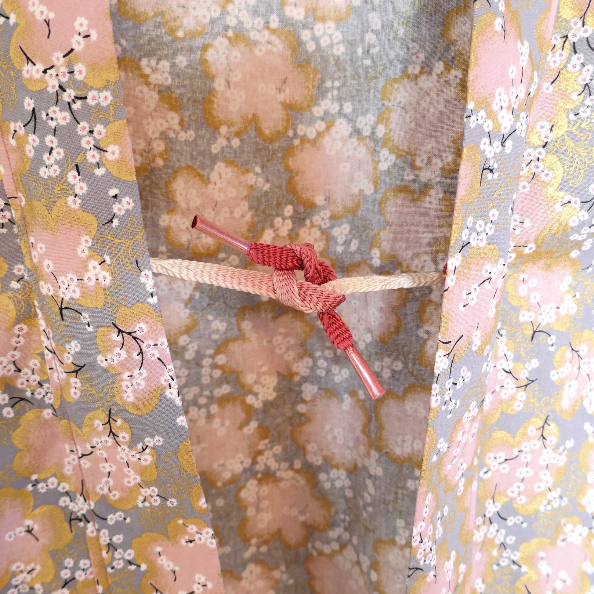 Attache haori traditionnelle rouge et crème sur tissu à fleurs de cerisier dorées