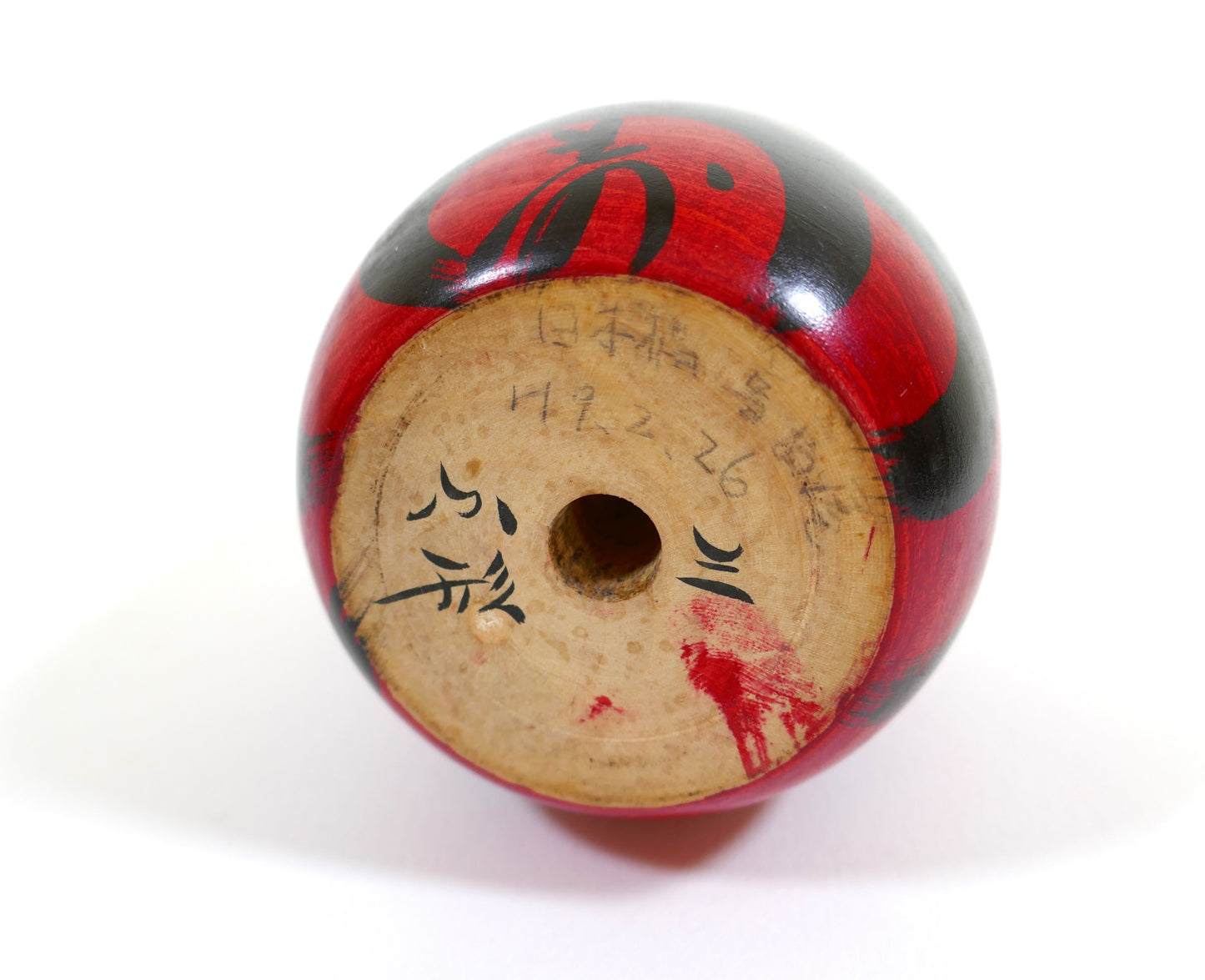Base d'une kokeshi Daruma japonaise peinte à la main, avec signature en kanji visible