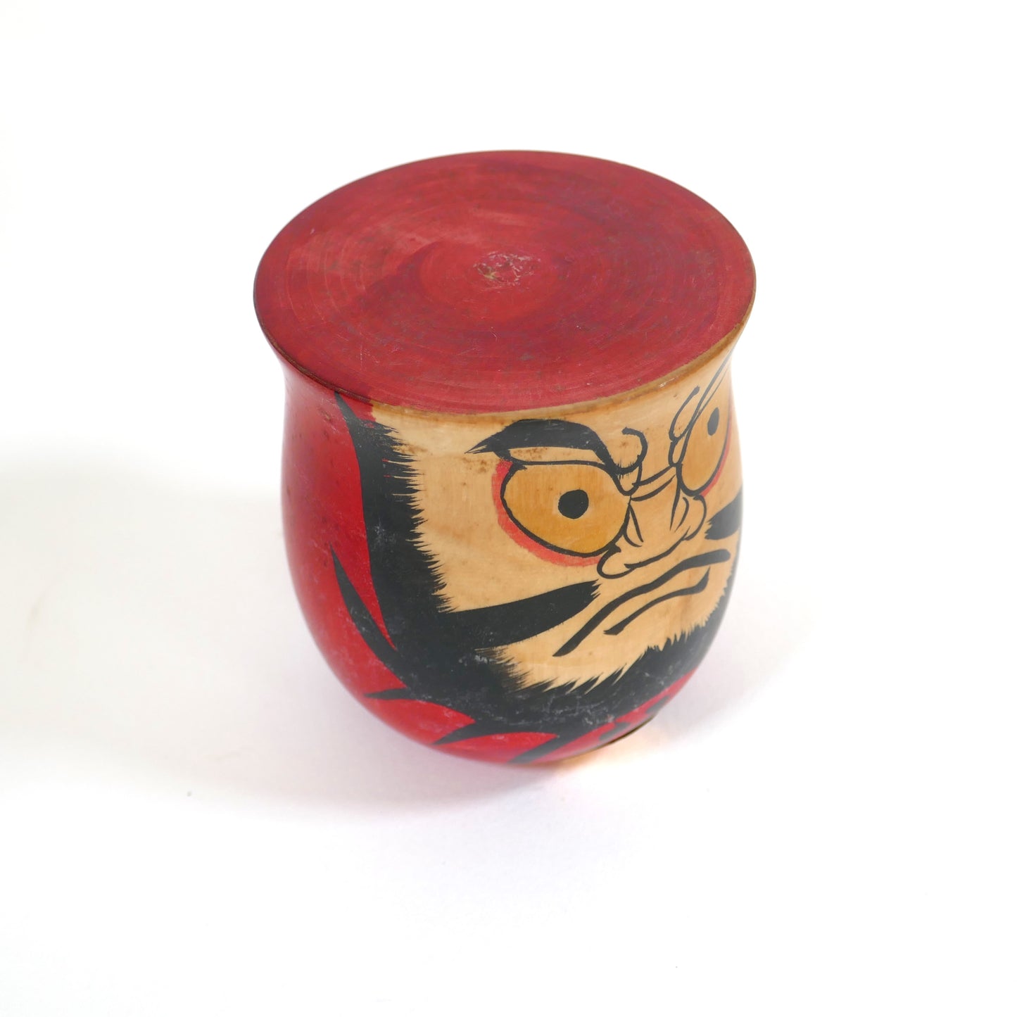 Kokeshi Daruma d’artisan japonais, vue en trois-quarts, peinture rouge et noire typique de l’époque Shōwa