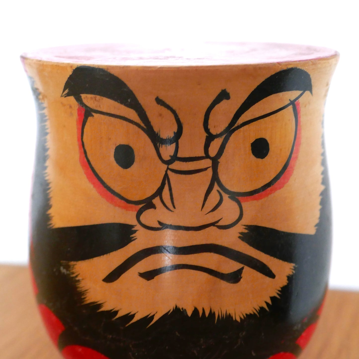 Gros plan sur le visage expressif d'une kokeshi Daruma vintage, peinture artisanale par Kawamura, époque Shōwa