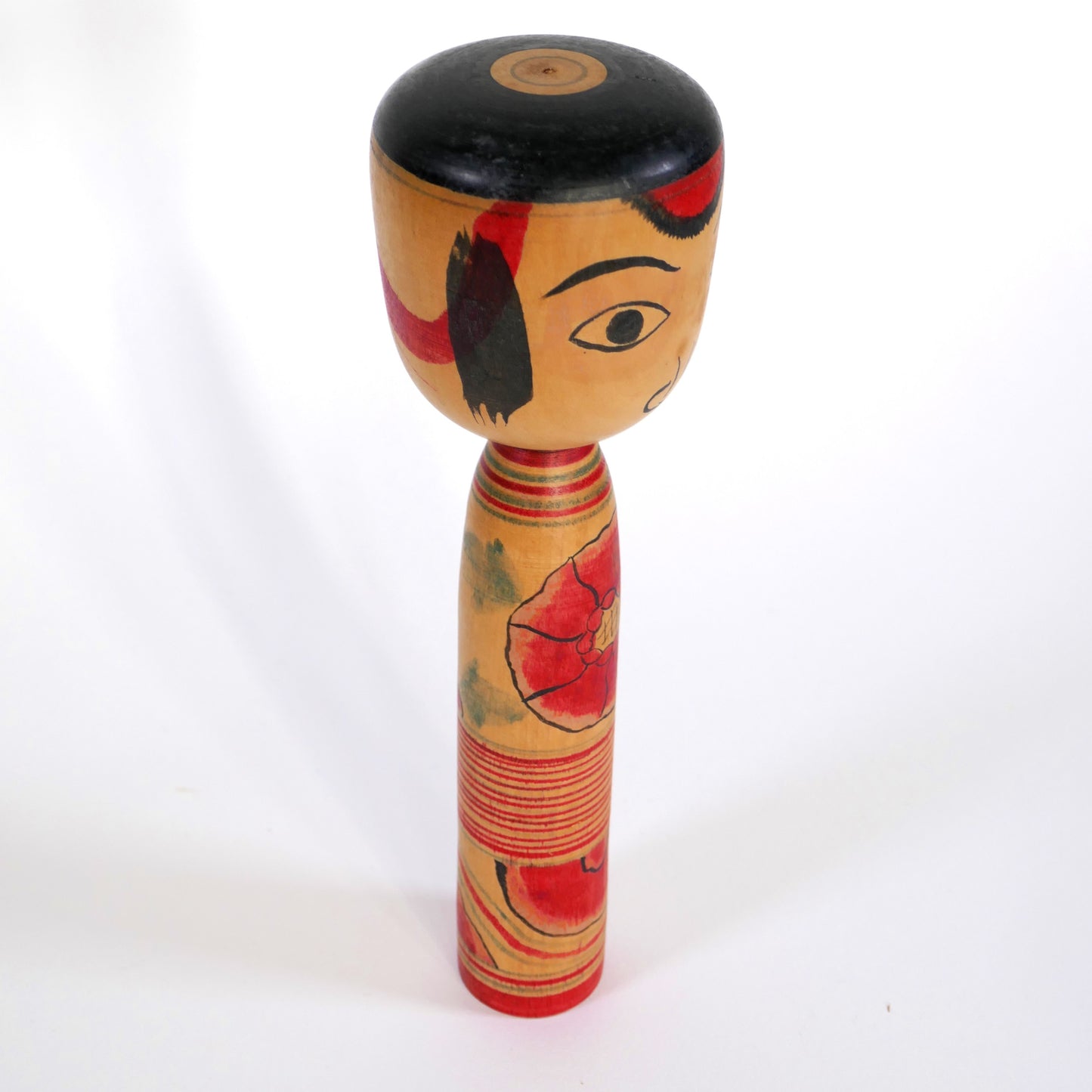 Profil d'une kokeshi Nakanosawa par Iwamoto Yoshizō montrant les mèches noires et fleurs rouges peintes