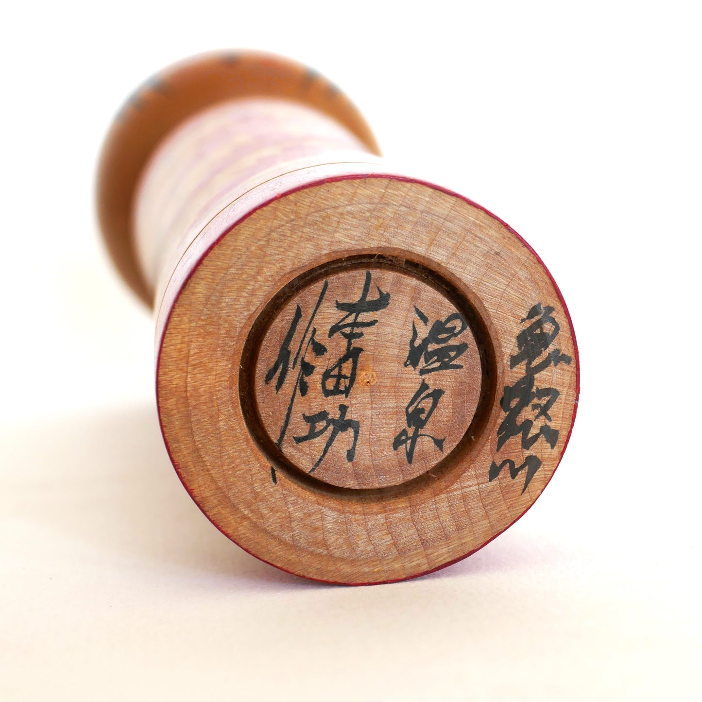 Signature japonaise sous la base d’une poupée kokeshi de Honda Isao, style Naruko.