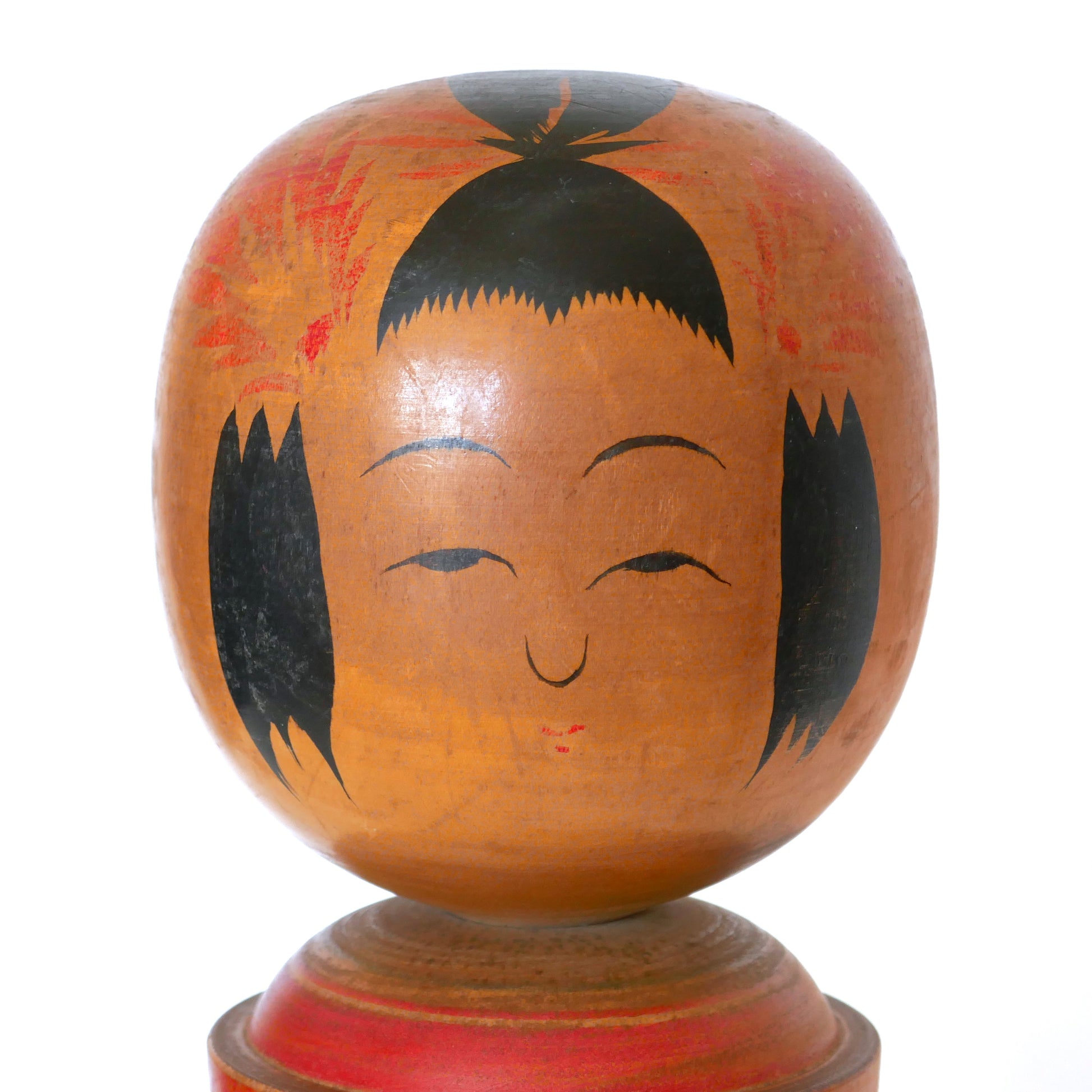 Gros plan sur le visage peint à la main d’une kokeshi de Naruko signée Hitoshi.