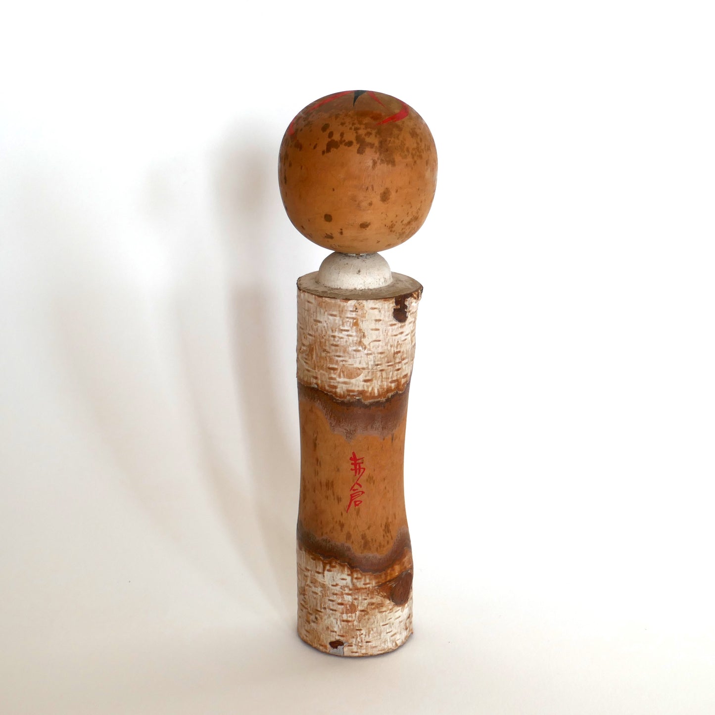 Vue arrière d’une kokeshi japonaise avec inscription en kanji rouge indiquant Akakura, station de montagne japonaise.