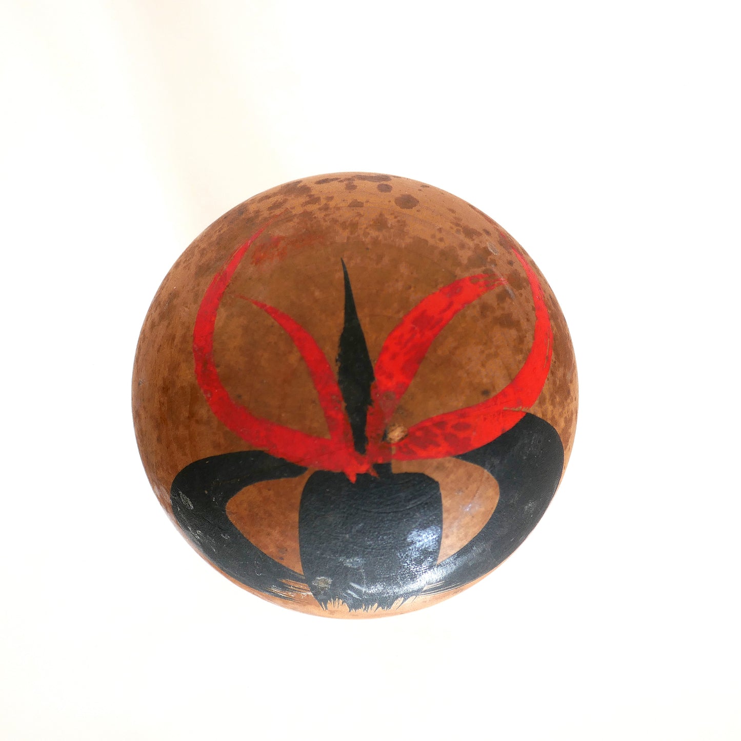 Motif floral rouge et noir peint sur le sommet de la tête d’une kokeshi poupée omiyage japonaise.