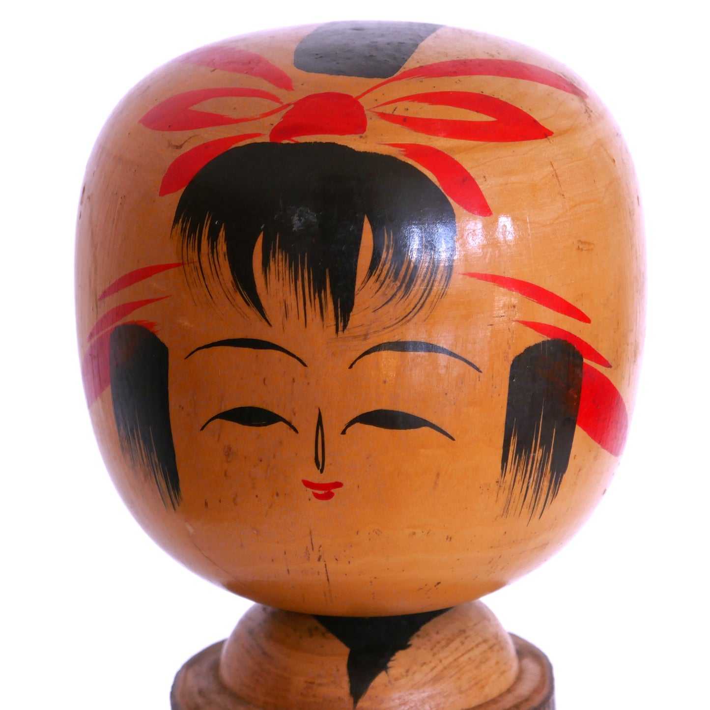 Visage souriant d’une kokeshi omiyage vintage – coiffe rouge stylisée et traits fins typiques des poupées souvenirs japonaises