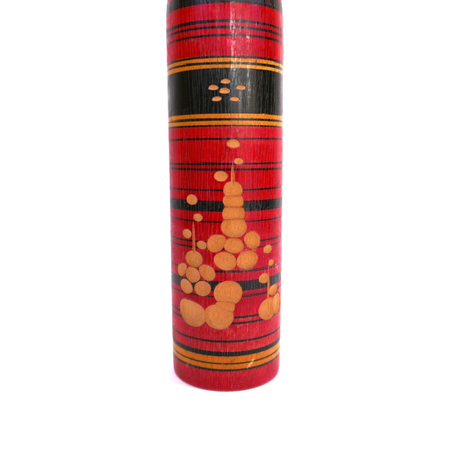 Détail du motif graphique jaune sur fond rouge au bas du corps de la kokeshi.