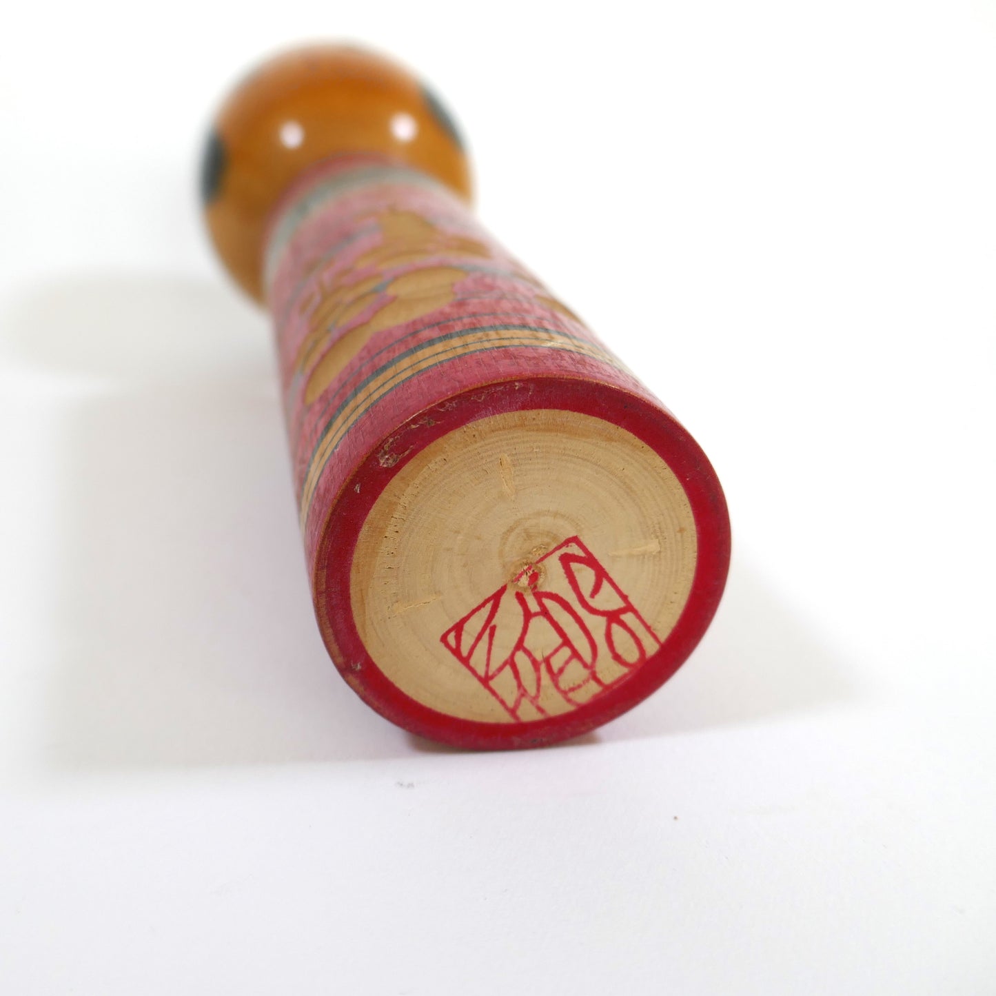 Signature au tampon rouge sous la base d’une kokeshi shingata par Katsumi Sasaki.