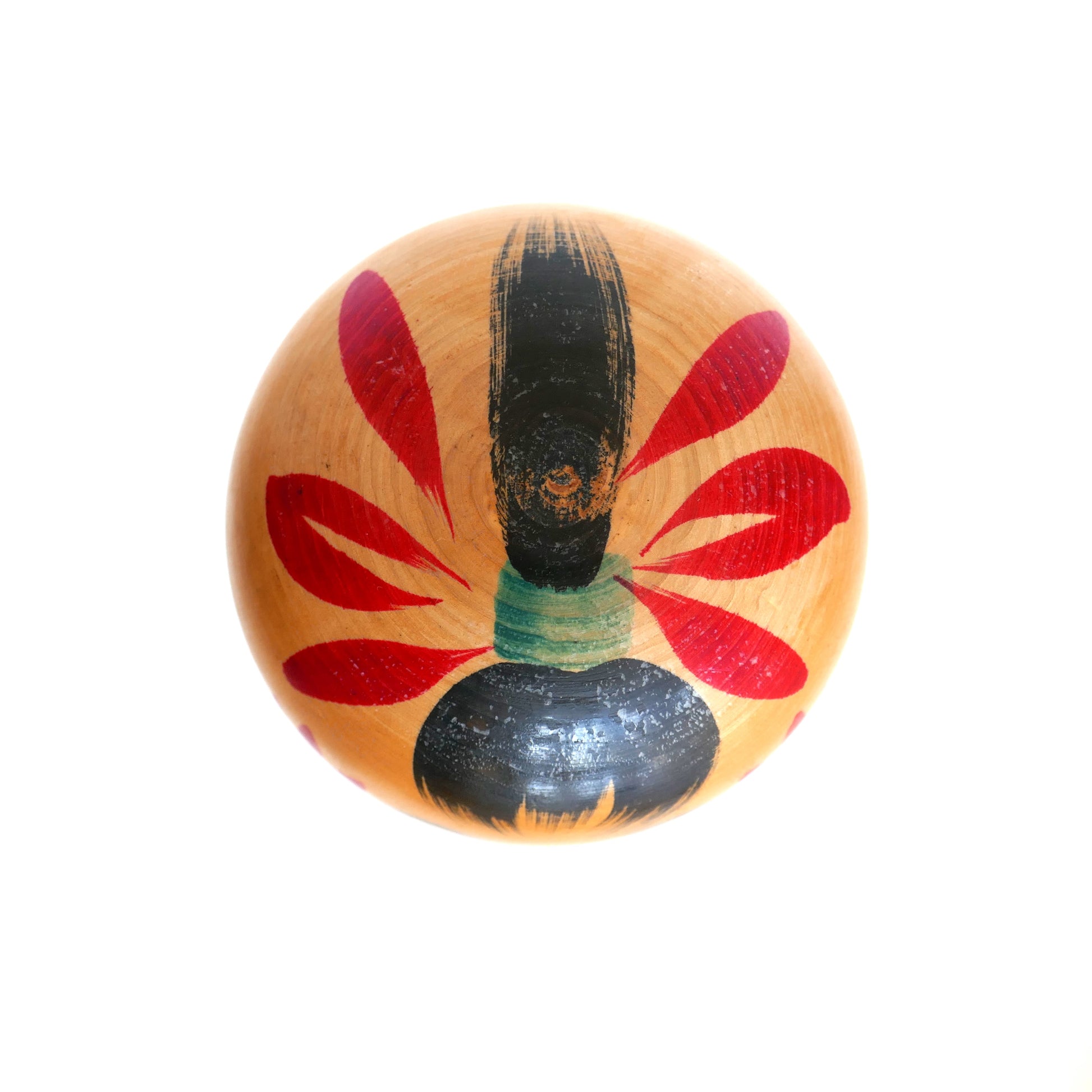 Vue du dessus de la tête d’une kokeshi artisanale, montrant la coiffure peinte