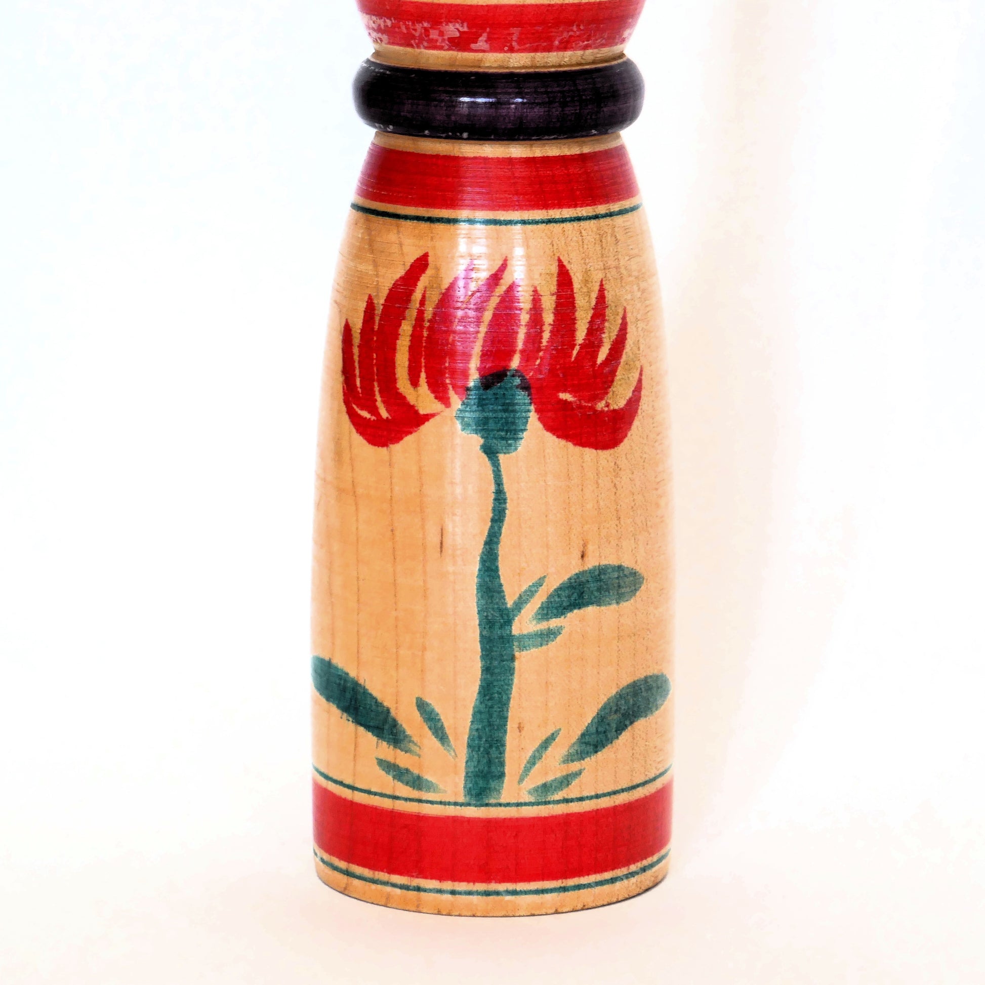 Détail des fleurs peintes sur le corps d'une kokeshi shingata de style Yajirō