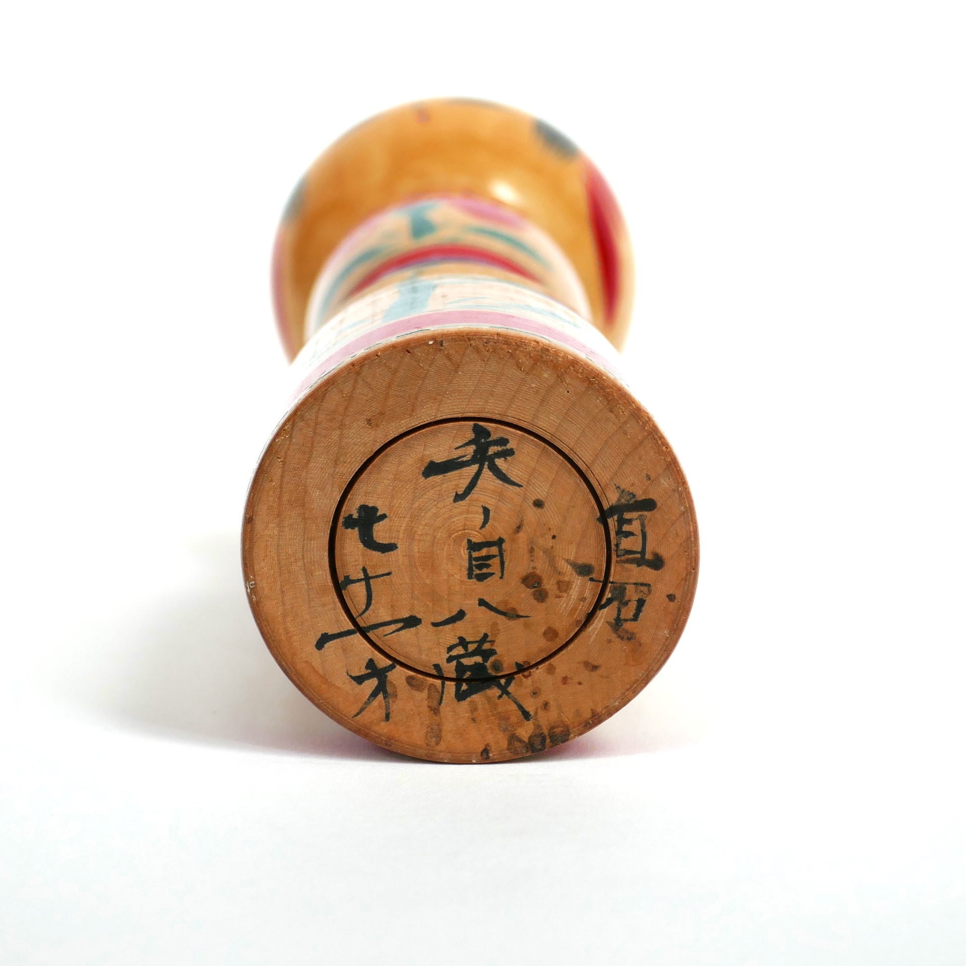 Signature manuscrite de l’artisan Yanome Hachizō sous une kokeshi du village de Shiroishi