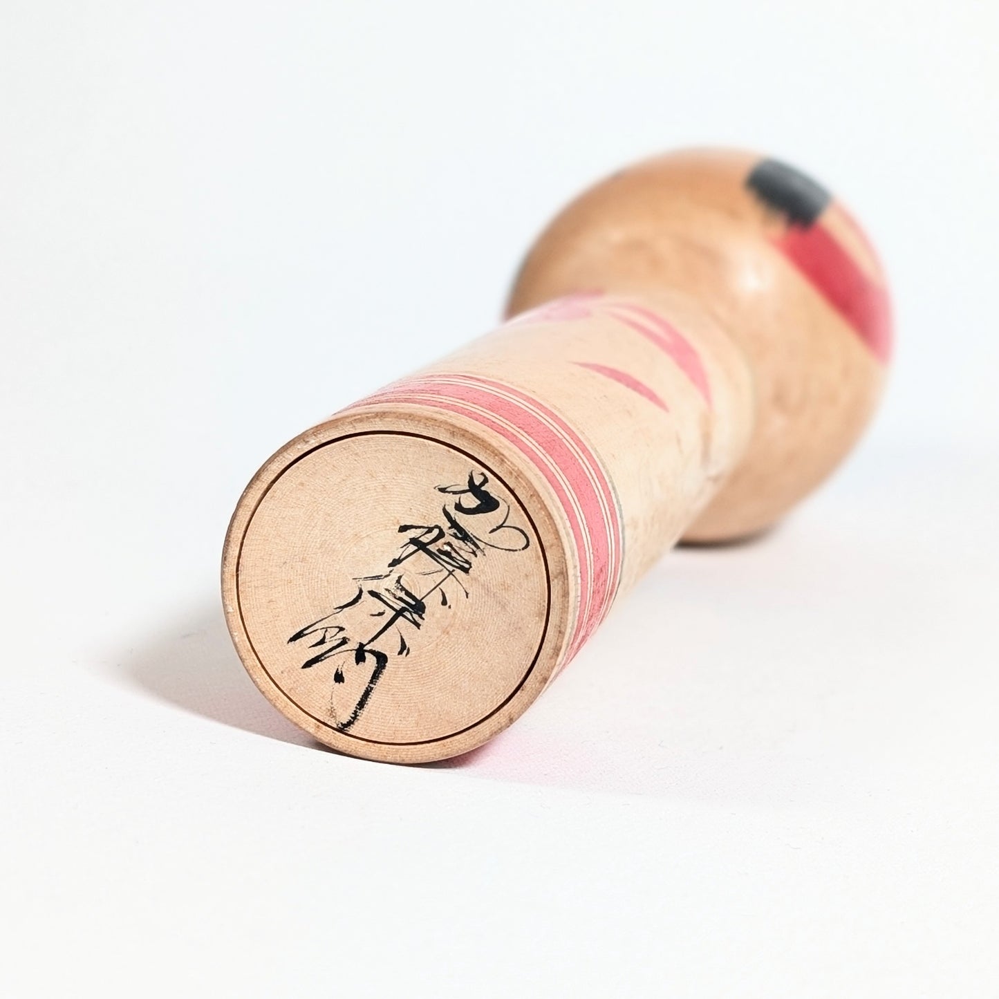 Signature de l’artisan Yasuaki Katō (加藤保明) sous une kokeshi traditionnelle japonaise.