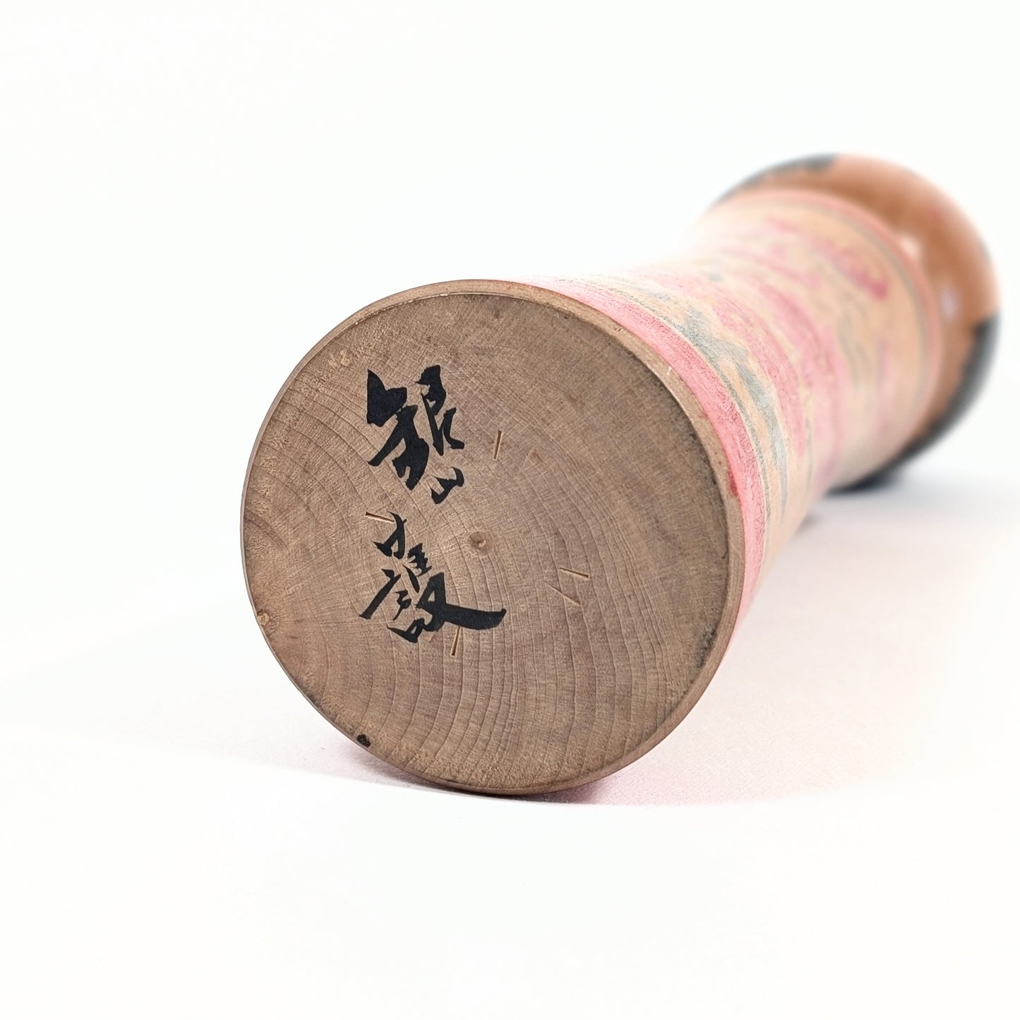 Signature sous la base d’une kokeshi Mamoru Izu, poupée japonaise artisanale signée de style Oshin Ginzan