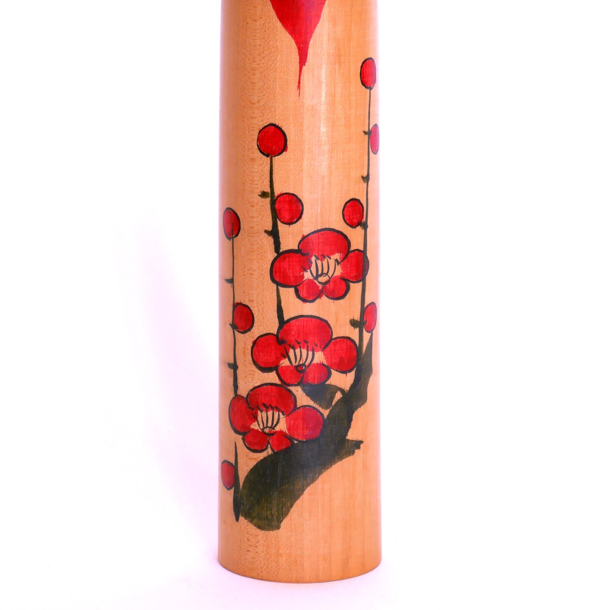 Détail du décor de fleurs de prunier rouges sur une kokeshi Togatta – peinture traditionnelle sur bois japonais