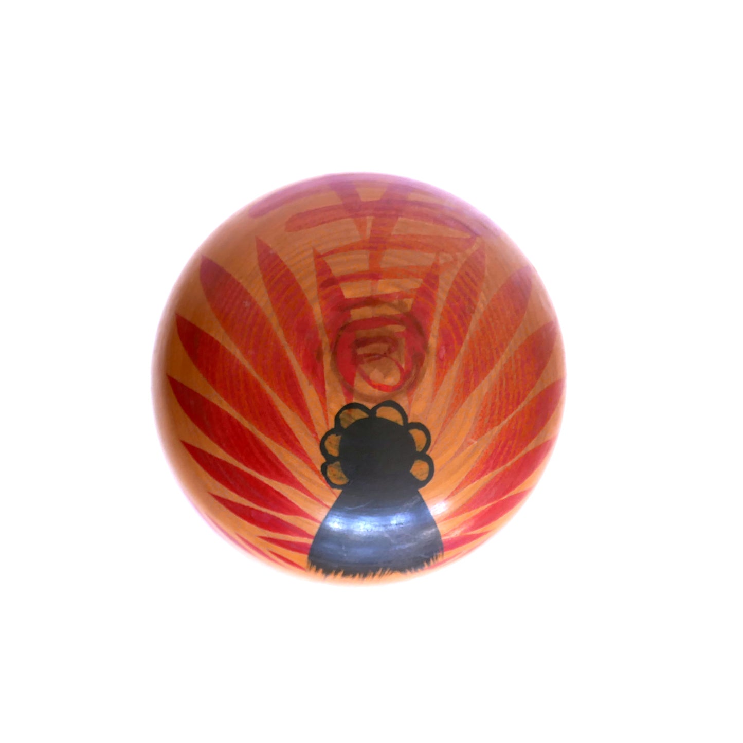 Vue du dessus de la tête d’une kokeshi Togatta – coiffure stylisée et motifs rouges rayonnants Tegara