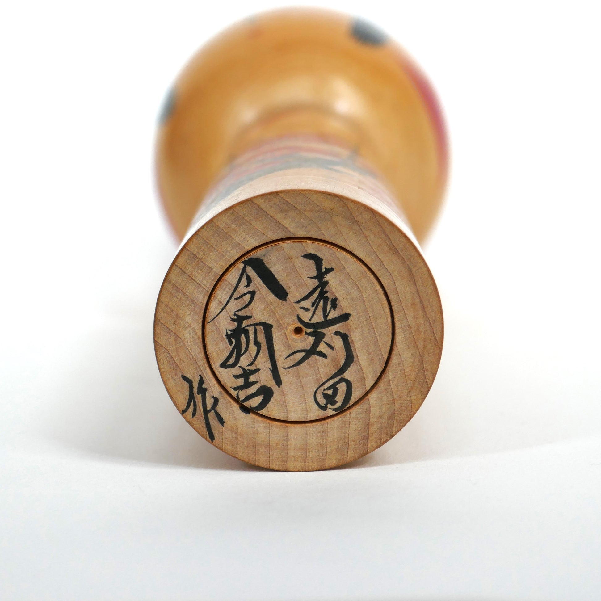 Signature artisanale de Satō Kesakichi sous une kokeshi Togatta – calligraphie japonaise sur bois brut