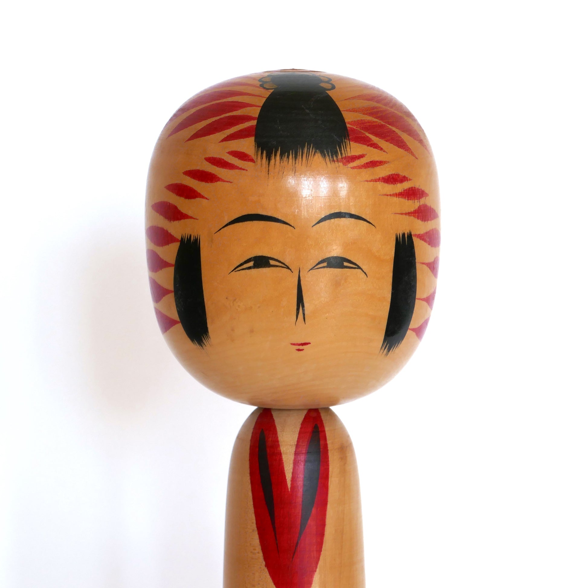 Gros plan du visage d’une kokeshi japonaise Togatta – expression fine et style caractéristique de Satō Kesakichi