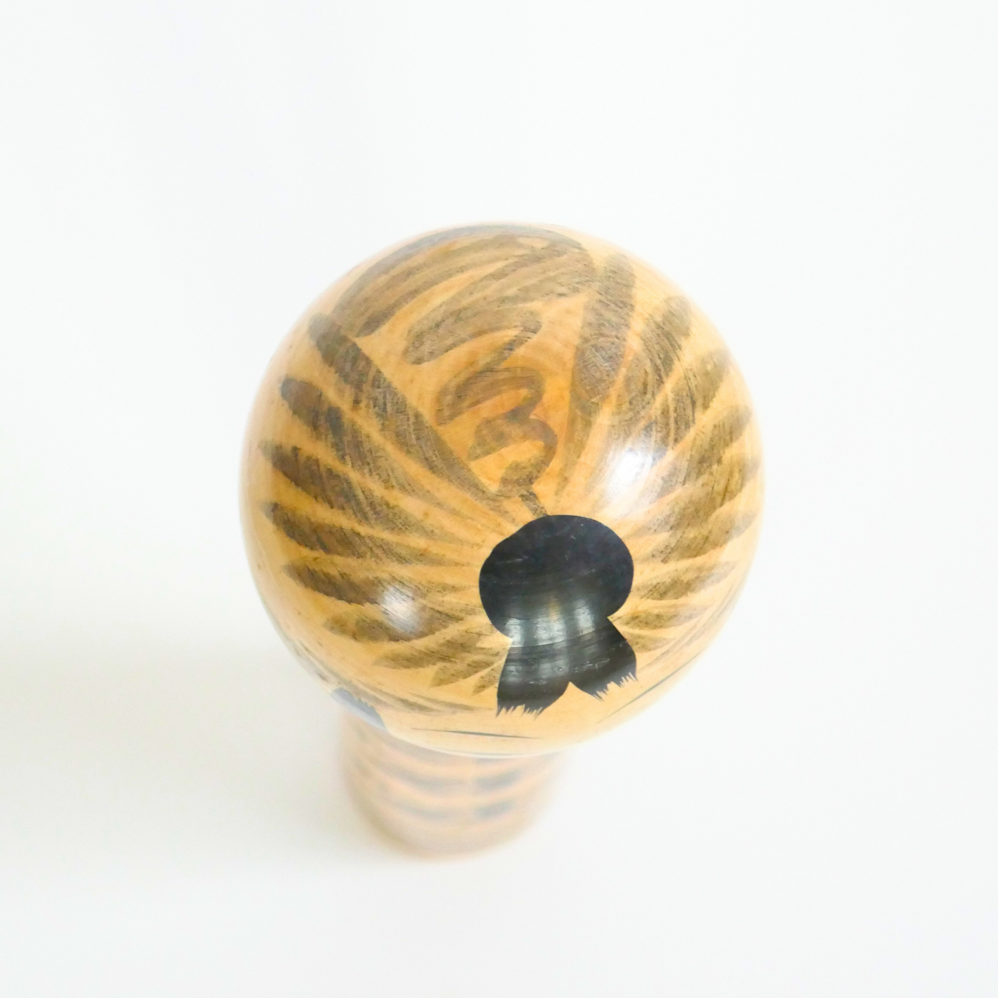 Vue du dessus d’une kokeshi Tôgatta avec peinture grise concentrique