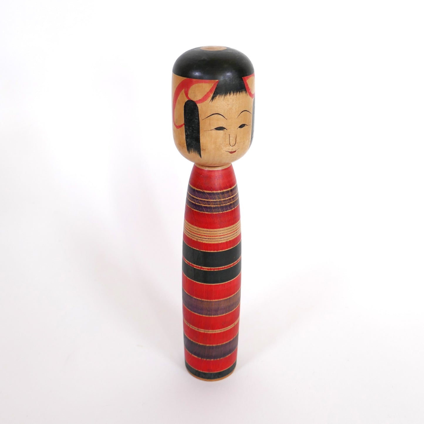 Profil droit d'une kokeshi vintage Tsuchiyu rouge et noir signée Sato Sashima