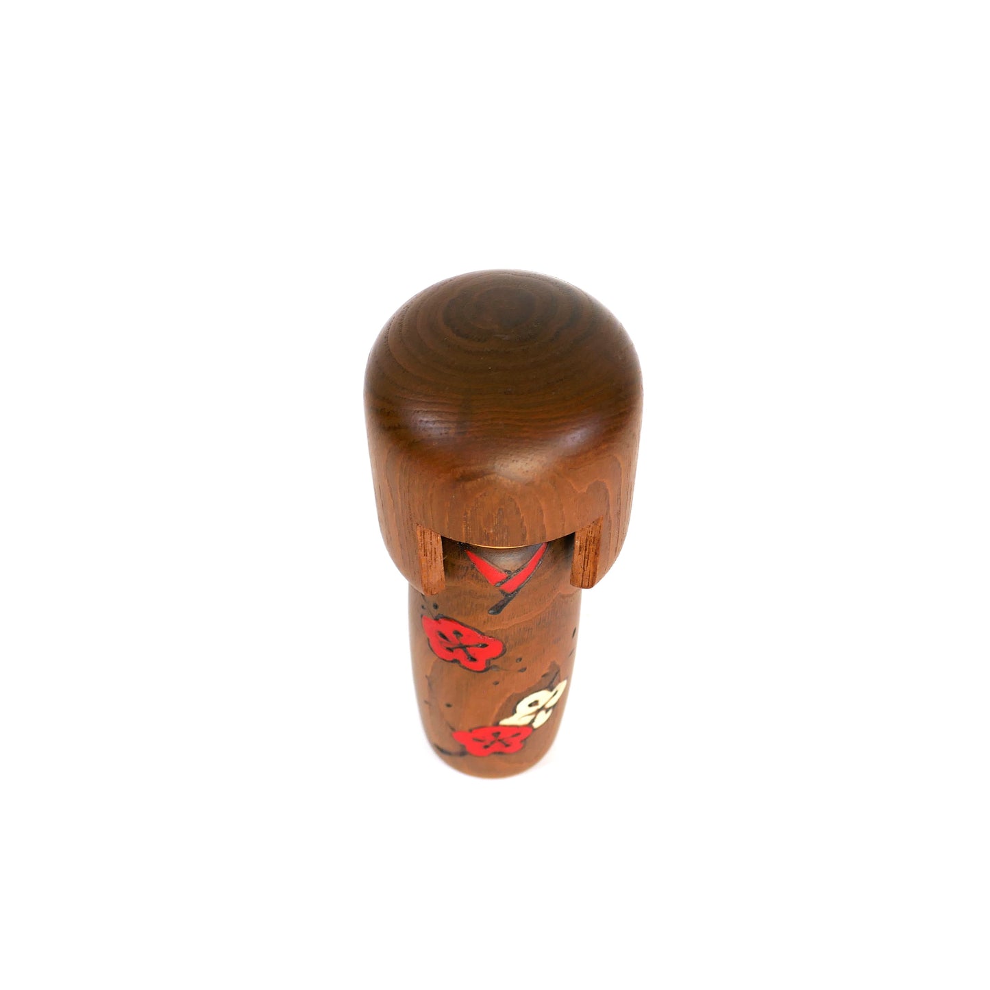 Vue du dessus d’une kokeshi Sosaku montrant la chevelure sculptée et les détails peints