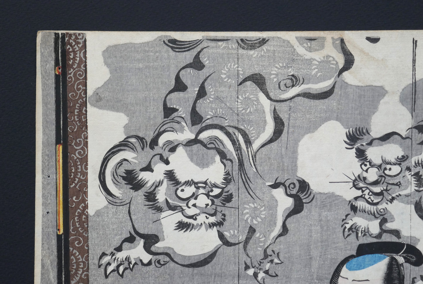 Coin supérieur gauche de l’estampe japonaise de Kuniyoshi : lions gardiens (shishi) sur fond de nuées devant un paravent, ukiyo-e gravure sur bois, Edo 1849–1850 (pièce kabuki Omegumi ni uruo Iwafuji).