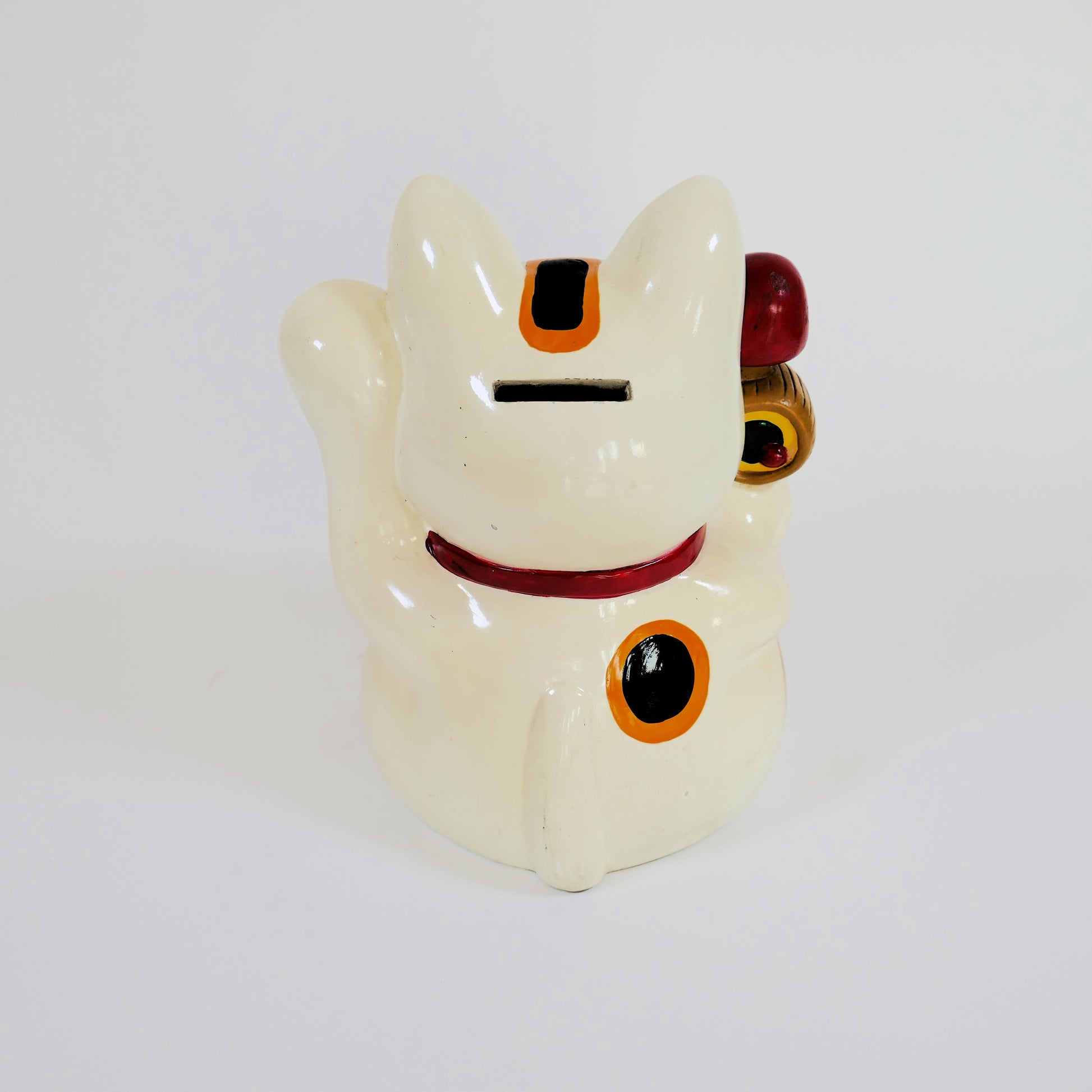 Vue arrière du maneki neko montrant la fente de la tirelire et les marques de fabrication.