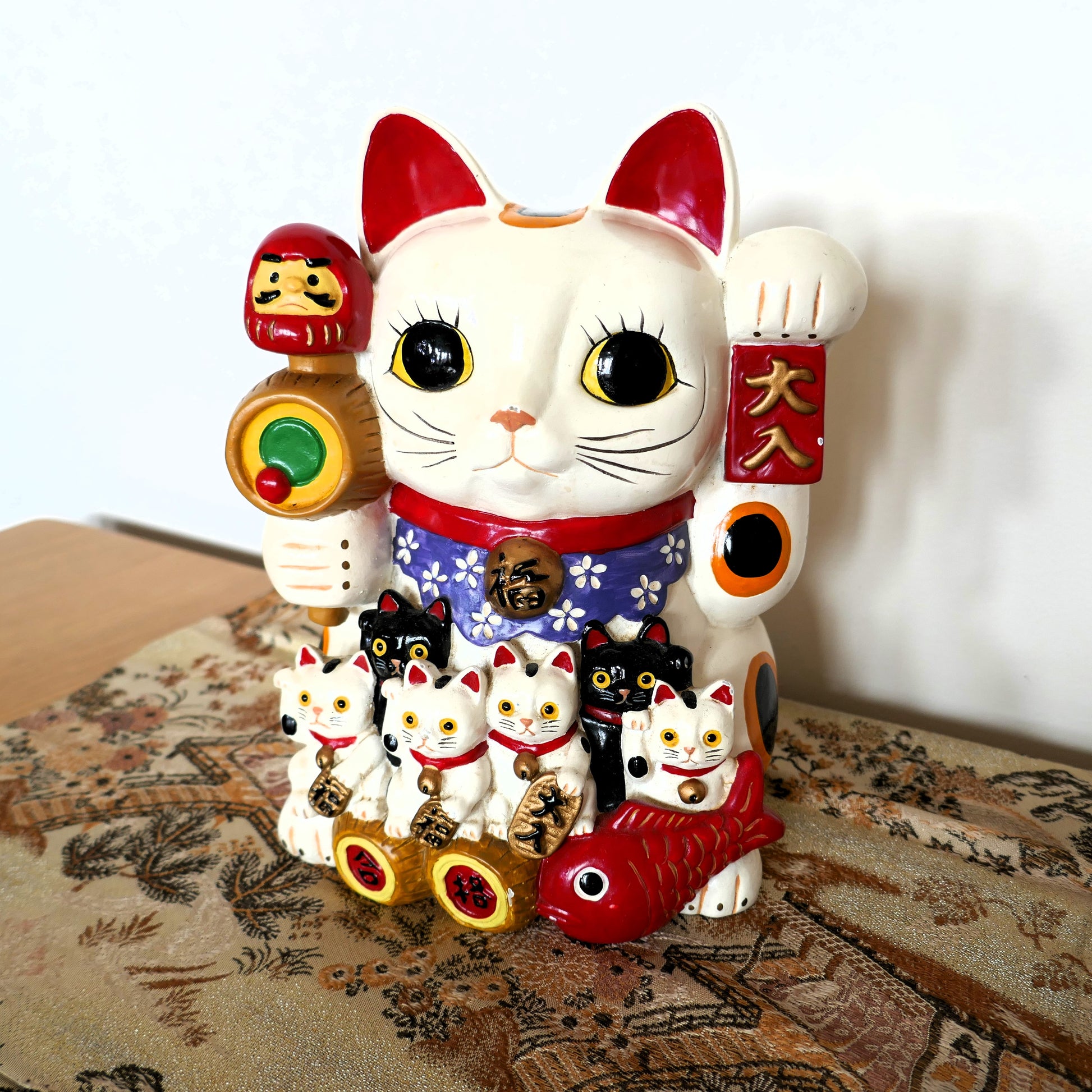 vue de face d'un maneki neko chat porte bonheur japonais kogedo mis en scene sur un obi