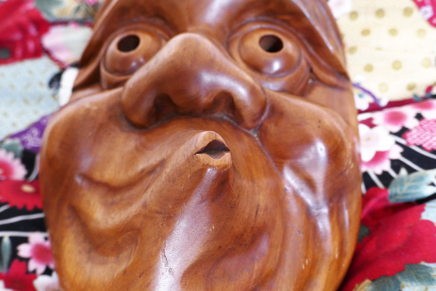 Gros plan sur la bouche tordue du masque Hyottoko, caractéristique du personnage comique soufflant du feu.