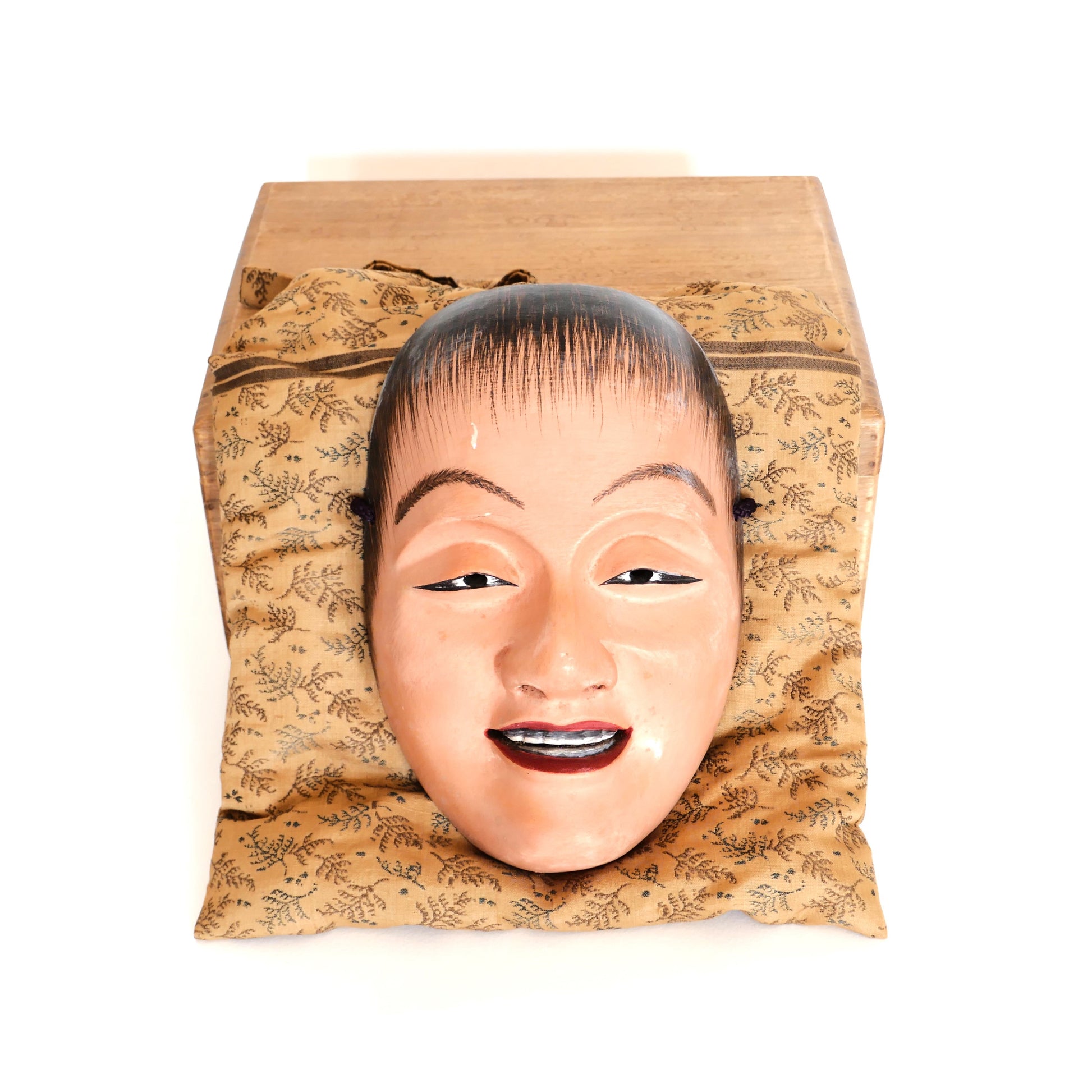 Masque Nô Doji sur coussin avec couvercle en bois visible – objet ancien japonais