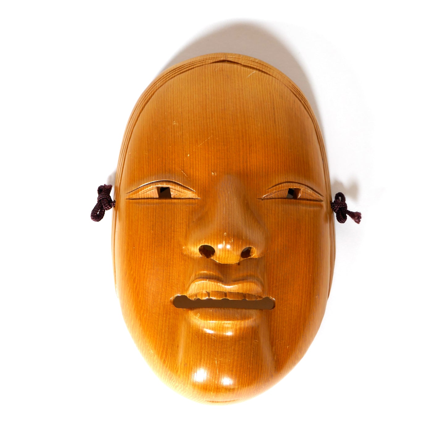 Masque Nō Ko-Omote avec éclairage venant du bas représentant une jeune femme japonaise souriante en bois sculpté