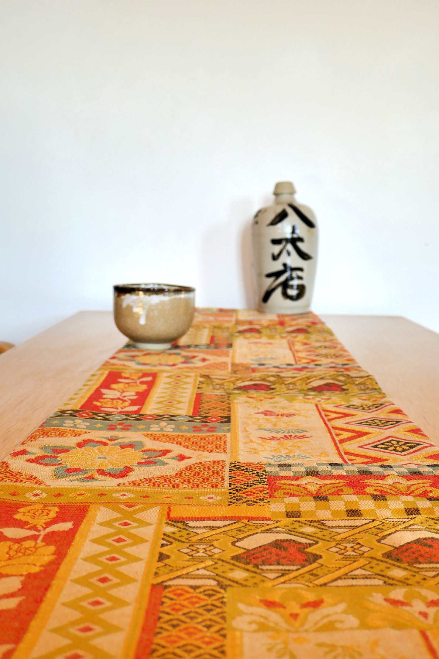 Mise en scène d’un obi ancien japonais en soie à motifs colorés sur table en bois