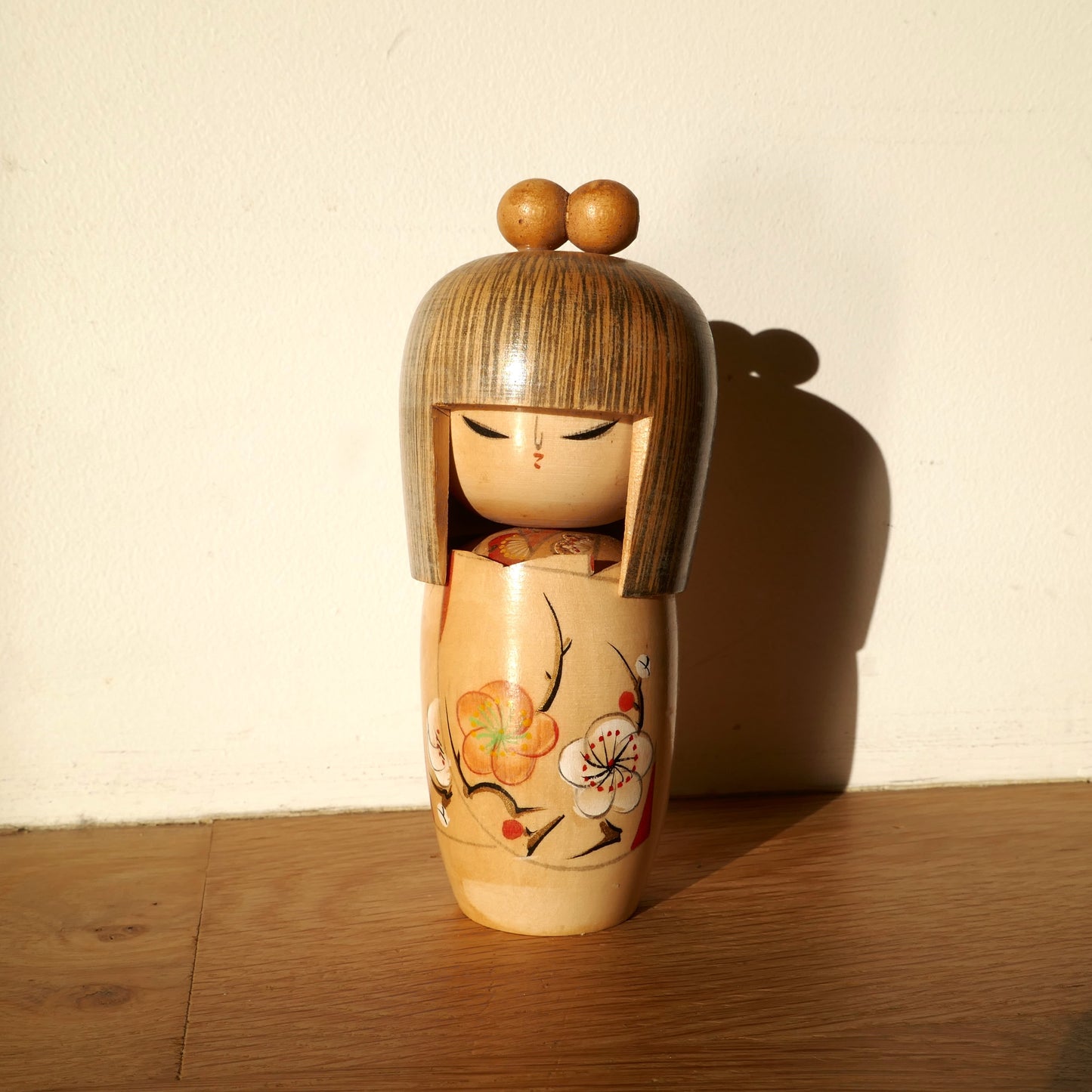 Poupée kokeshi artisanale en bois par Shigemi Tanaka alias Kojo Tanaka, sous lumière naturelle avec ombre
