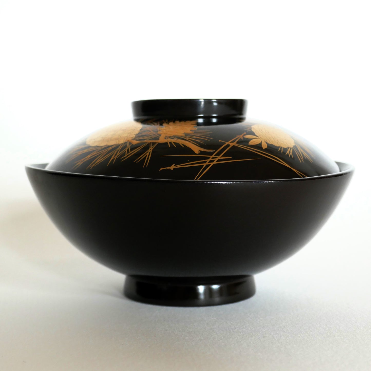 Bol japonais en laque urushi noire vu de profil, couvercle fermé avec décor doré de pin – style Wajima