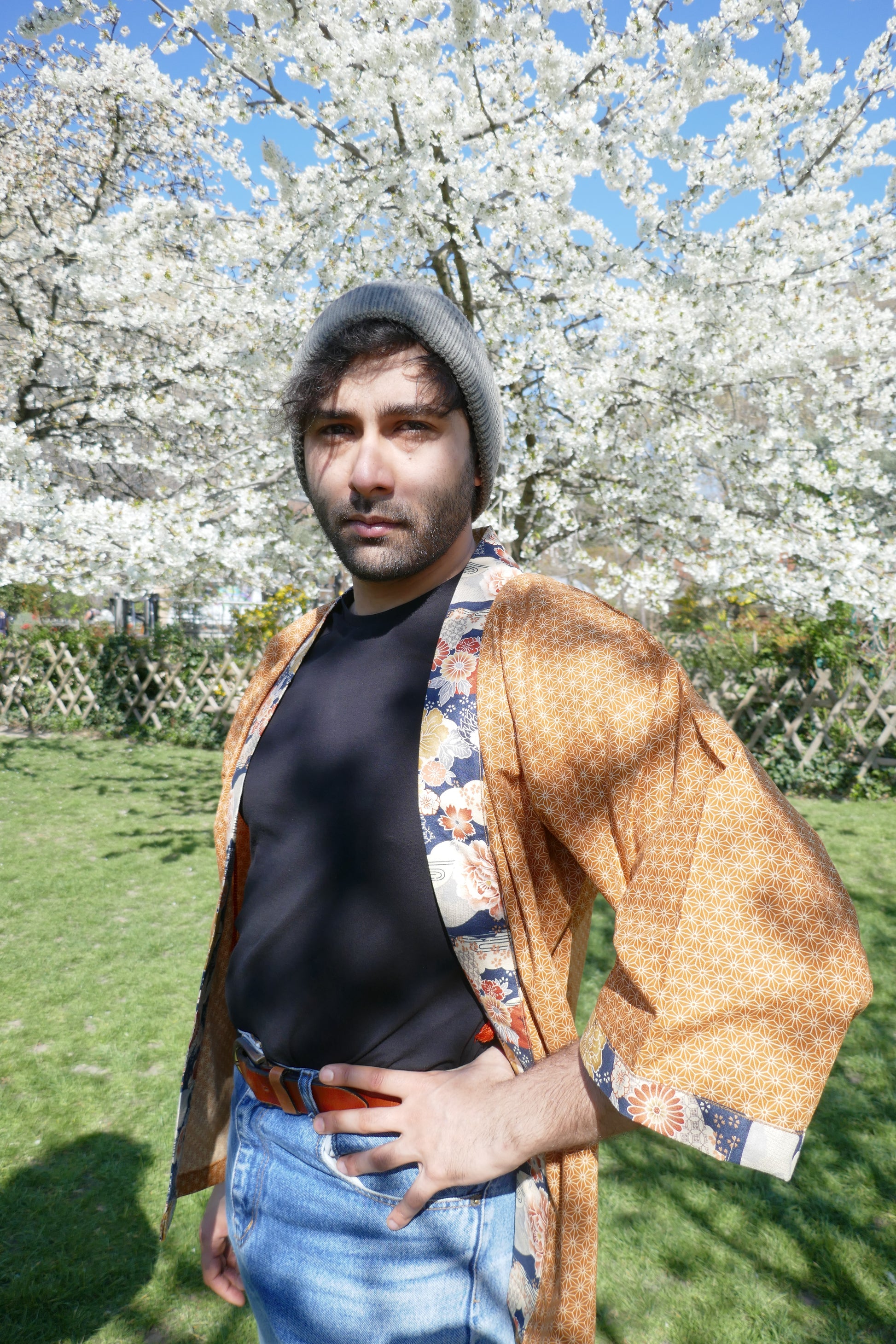 Richard en haori Yūyake Zakura debout devant un cerisier en pleine floraison.