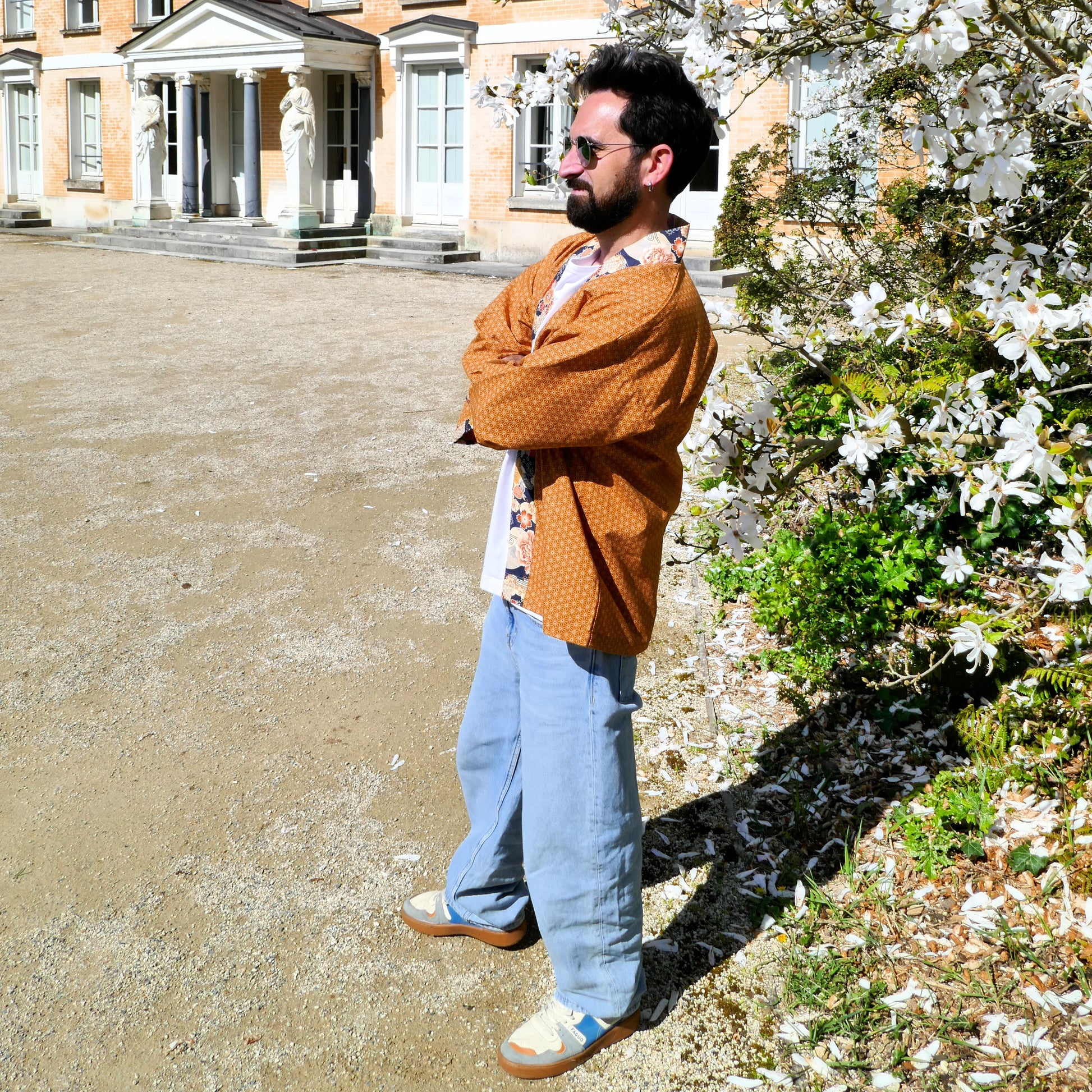 Tôma de profil en haori Yūyake Zakura, devant les fleurs blanches printanières.