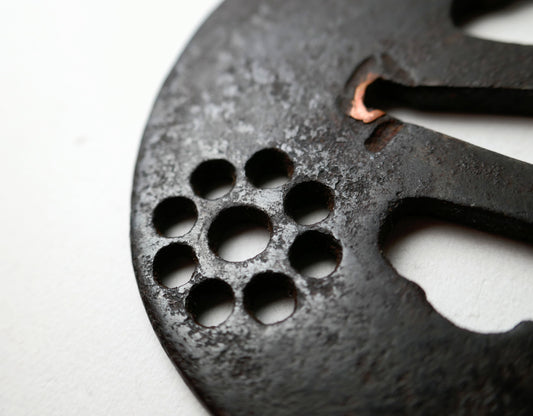Détail du Kuyō-mon en ko-sukashi sur une tsuba de samouraï ancienne, antiquité japonaise en fer à patine profonde.
