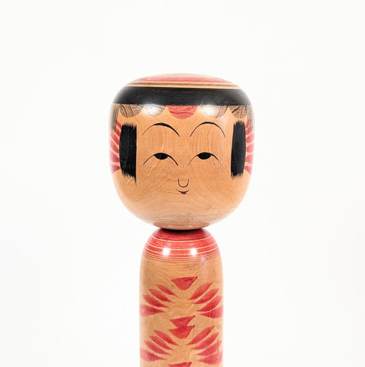 Gros plan sur le visage peint de la kokeshi Yajirō par Kamata Kōichi, avec frange noire et traits traditionnels délicats.