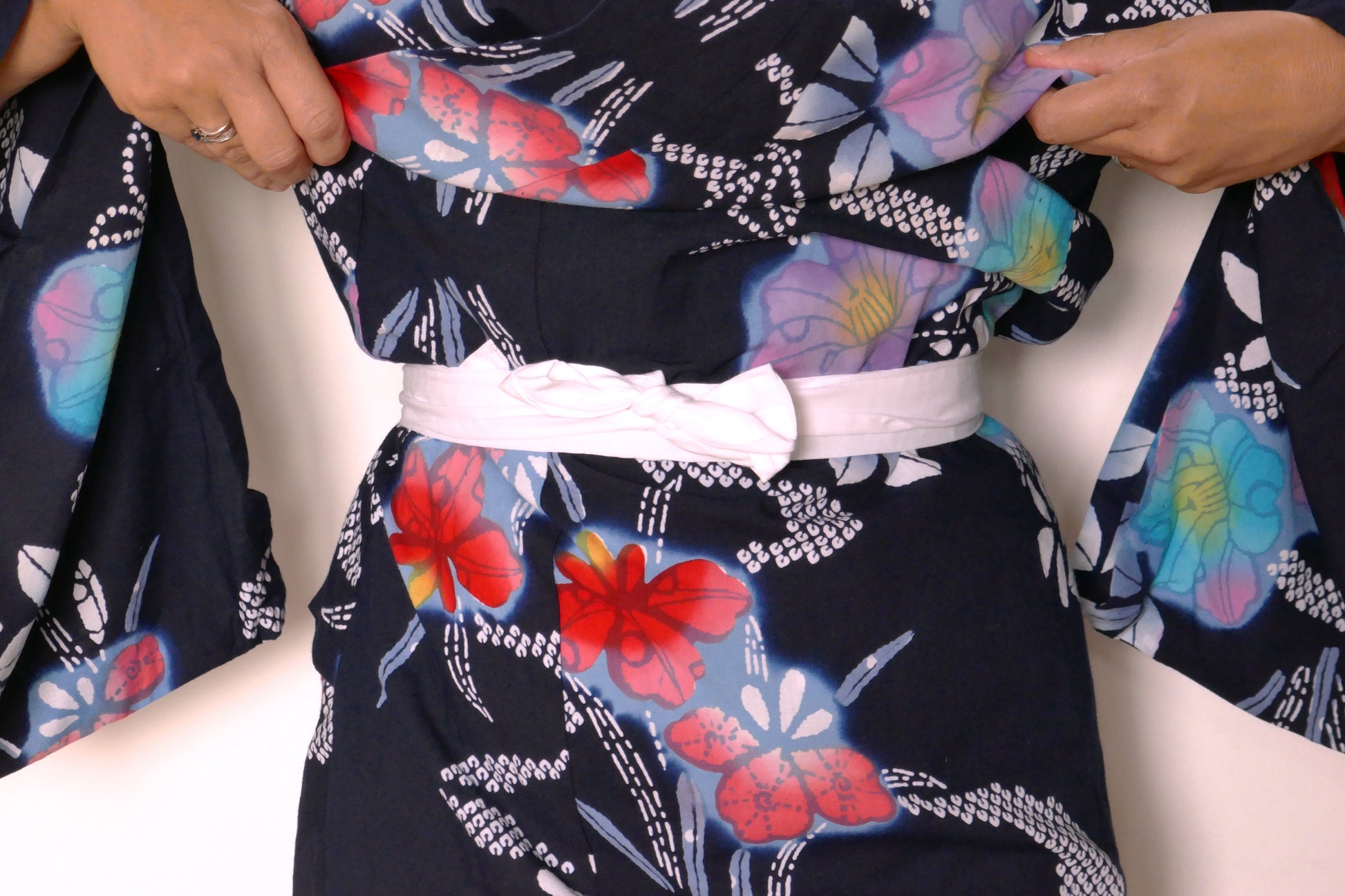 Gros plan sur le koshimo blanc noué sur un yukata fleuri en coton.