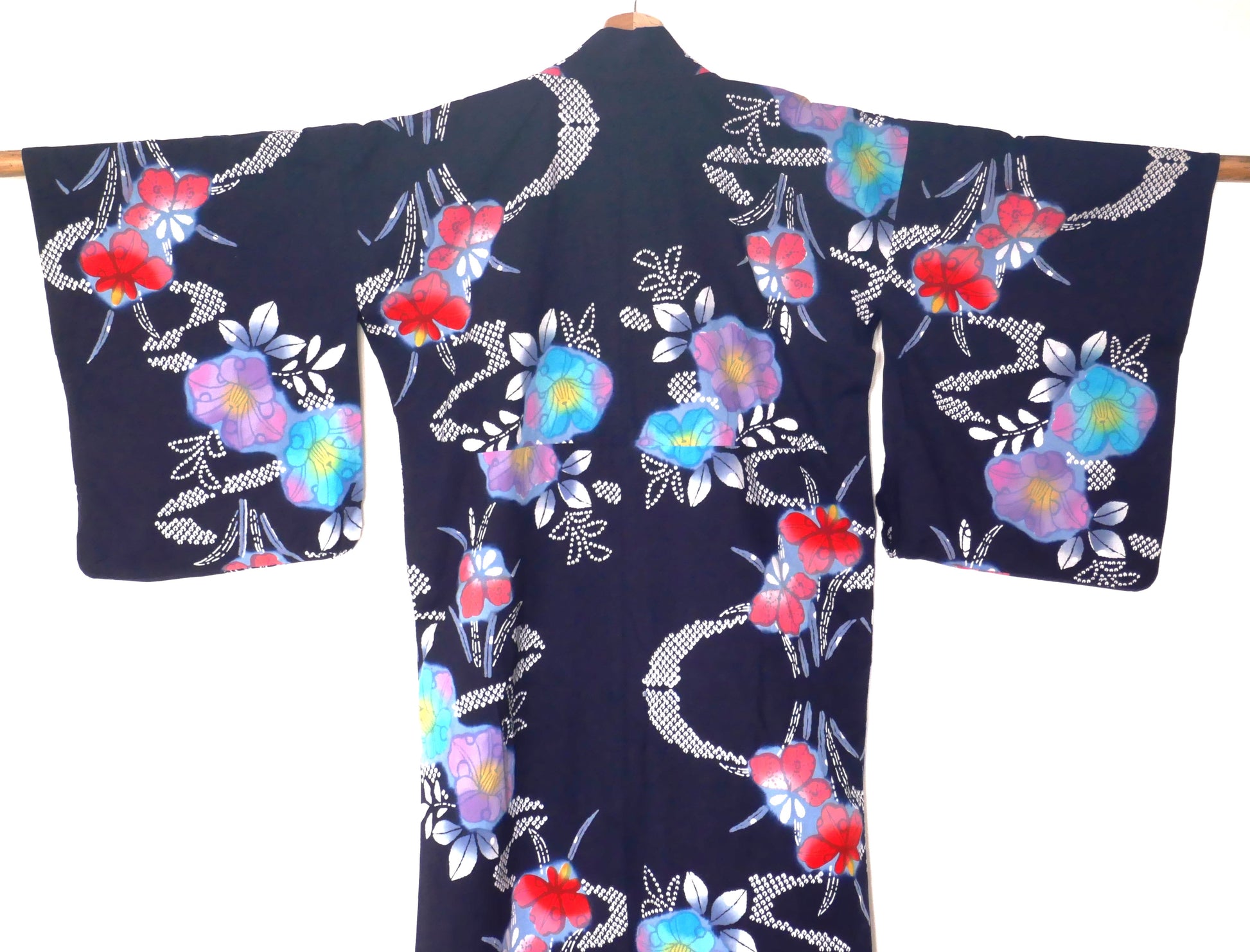 Dos d’un yukata bleu marine à fleurs multicolores typique de l’été japonais.