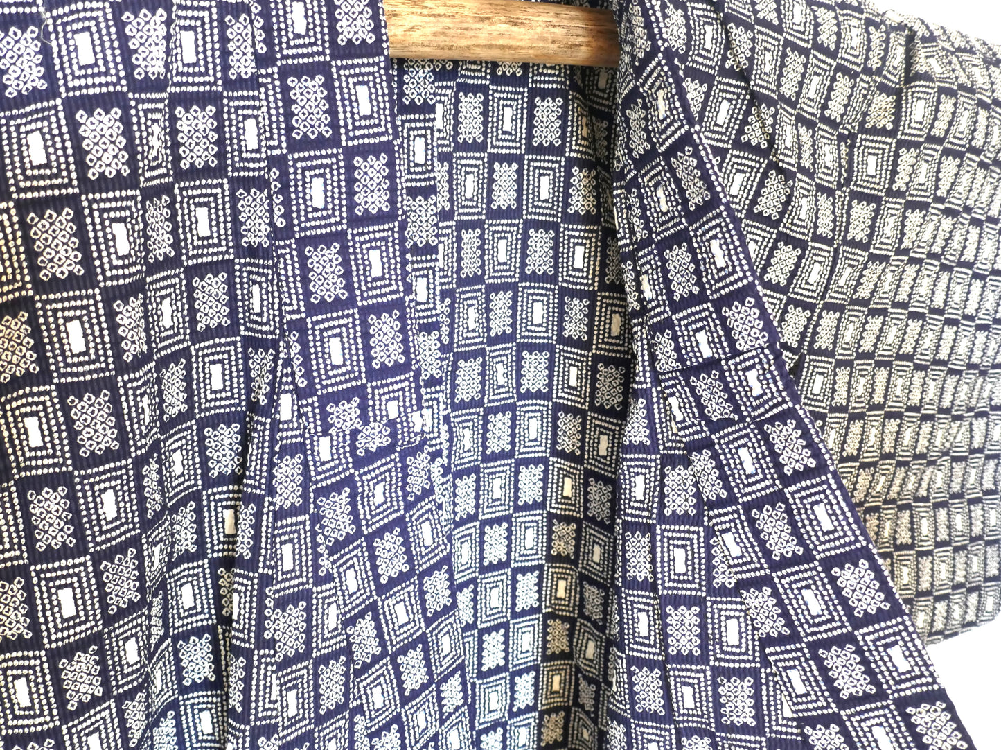 Gros plan sur le col du yukata, révélant les motifs géométriques blancs et la texture du coton crépé.
