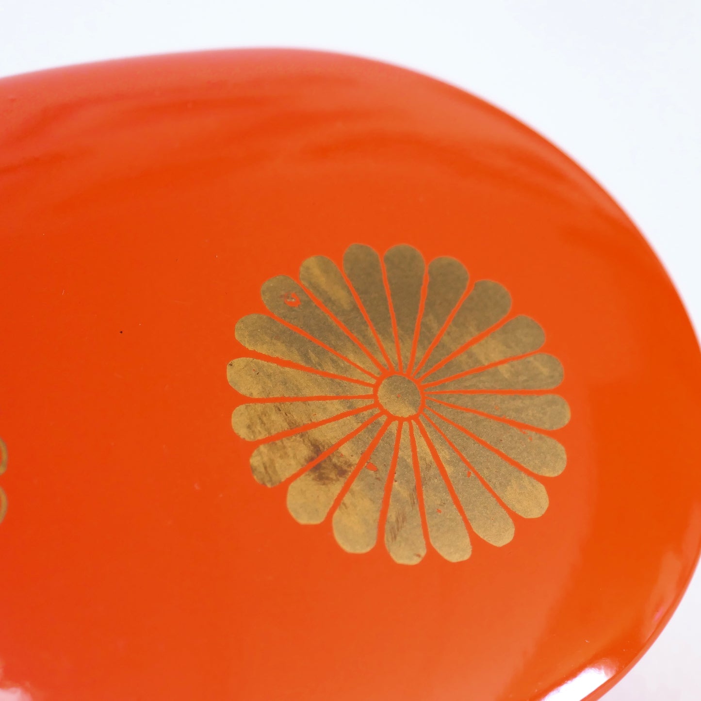 zoom sur le motif fleuri kiku doré d'une boite en laque orange japonaise